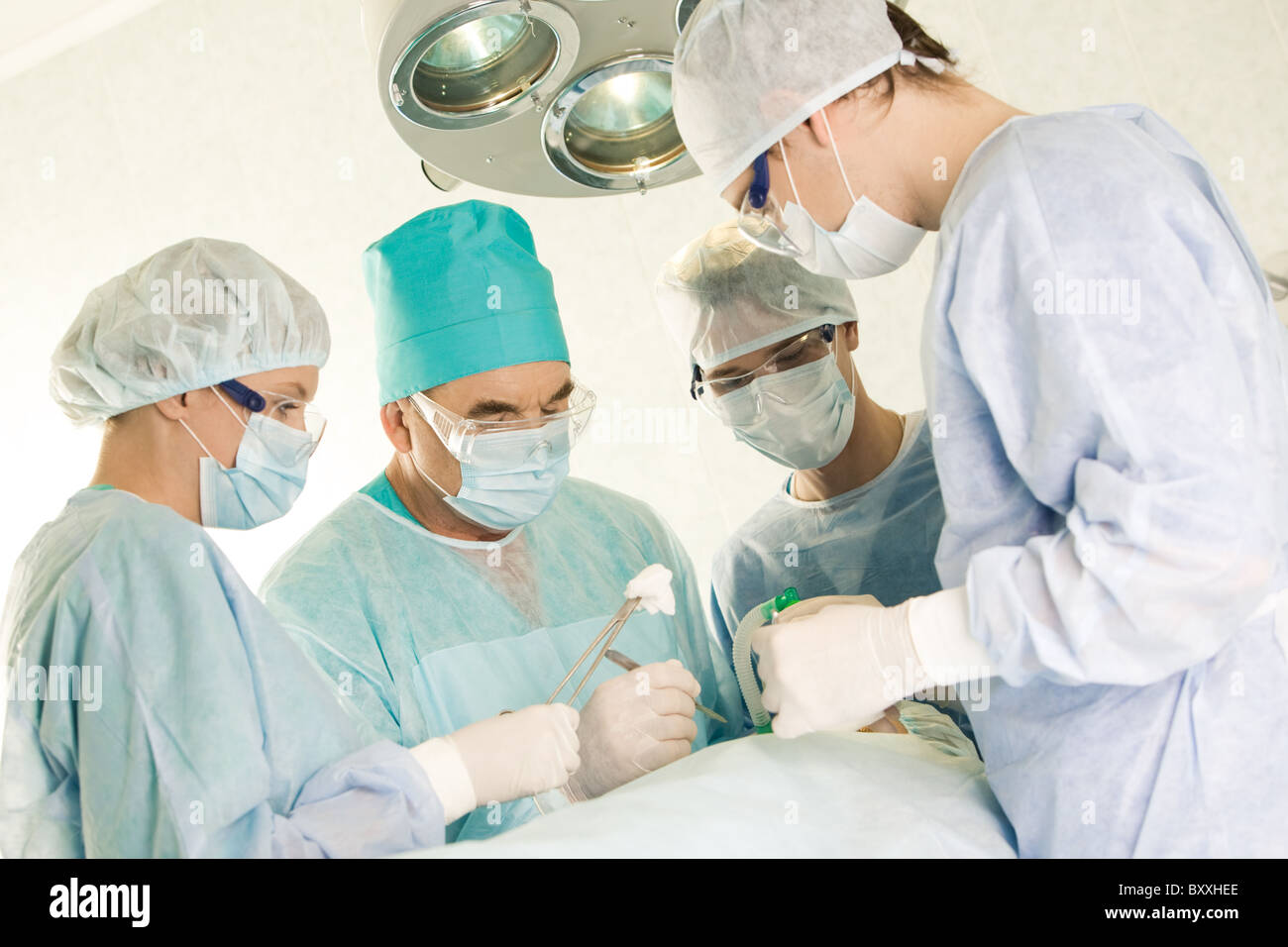 Plusieurs chirurgiens entourant patient sur table d'opération pendant leur travail Banque D'Images