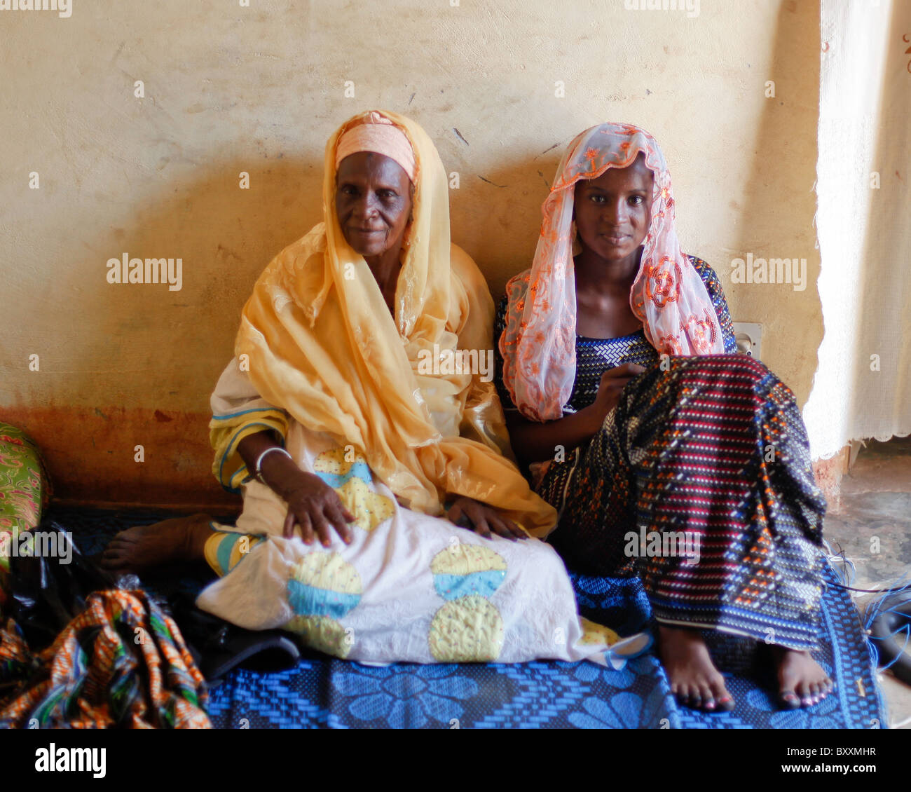 Un vieux et jeune femme s'asseoir ensemble sur un tapis dans une maison à Ouagadougou, Burkina Faso. Banque D'Images