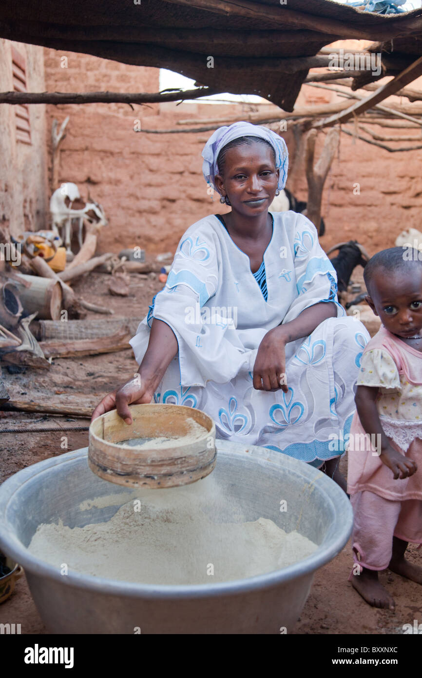 Une femme prépare la farine de mil pour la cuisson dans la ville de Djibo dans le nord du Burkina Faso. Banque D'Images