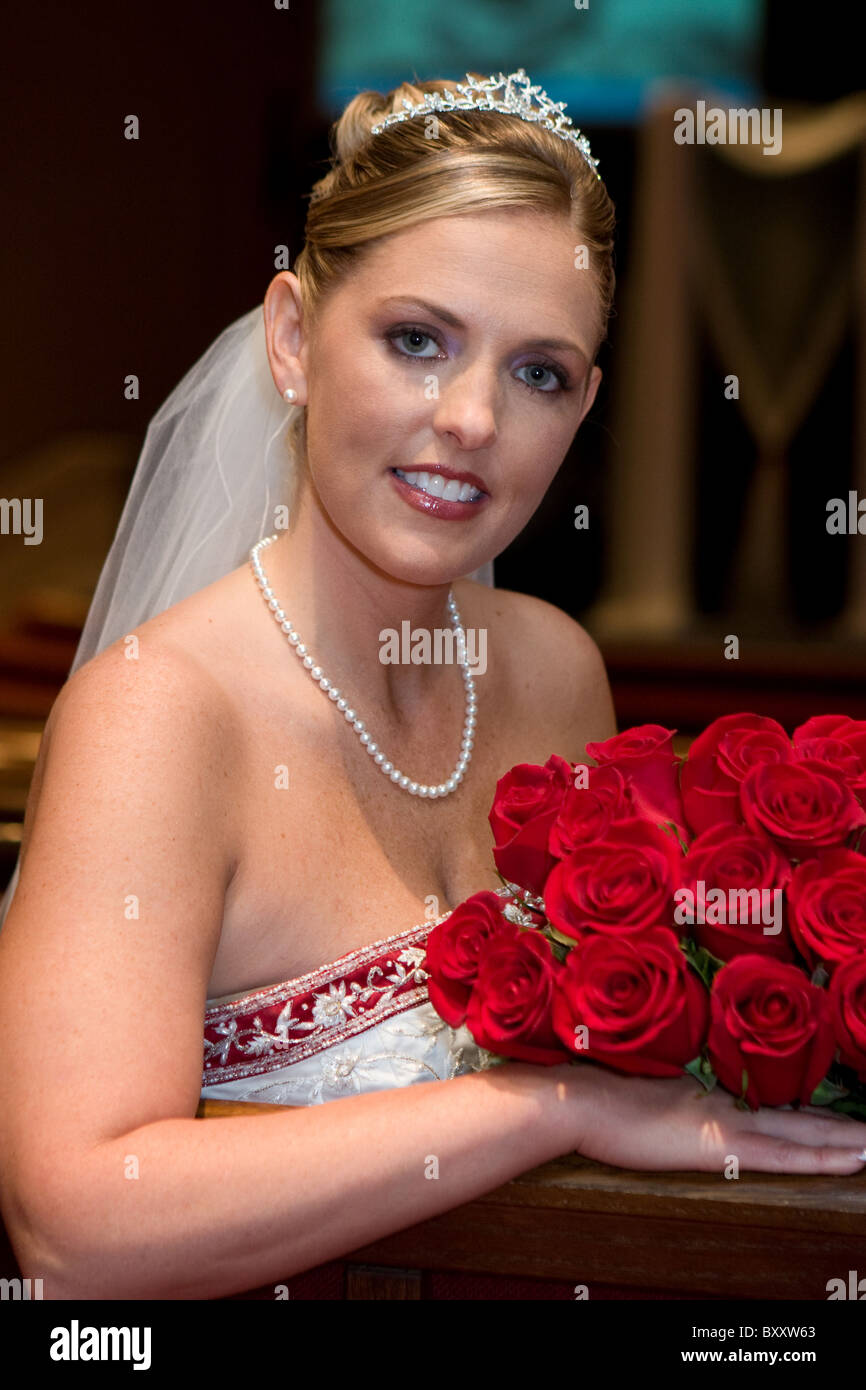 Belle Mariée avec un bouquet de roses pose pour les photos peu avant la cérémonie de mariage. Banque D'Images