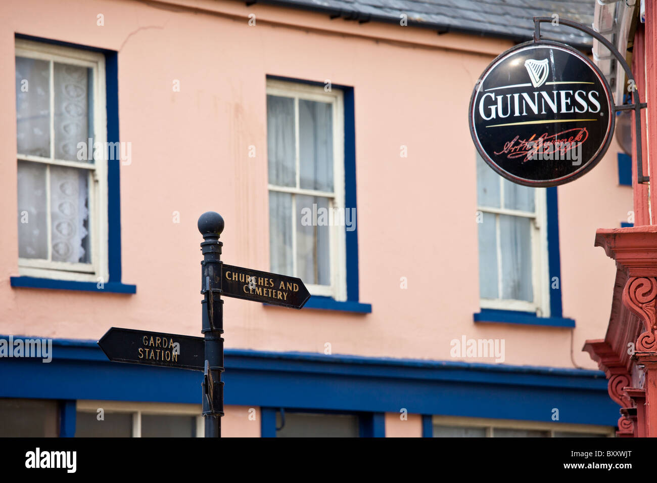 La marque d'une garde, les Églises et le cimetière à côté de publicité Guinness au bar dans la tour du lac, West Cork, Irlande Banque D'Images