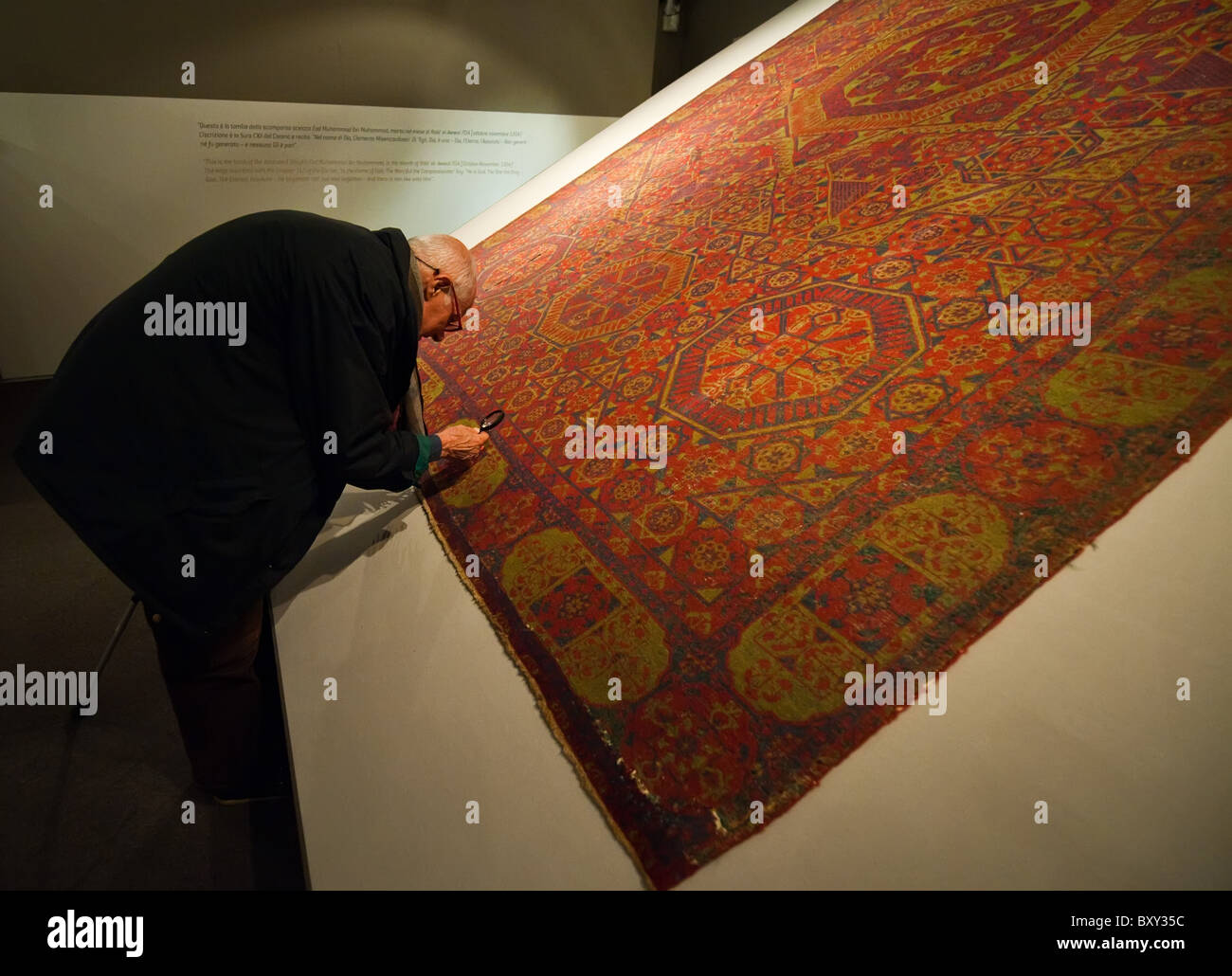 Un visiteur inspecte à la loupe un tapis de laine (XVI siècle) à de l'art de 'Al-Fann la civilisation islamique Banque D'Images