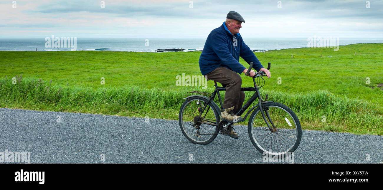 L'homme traditionnel irlandais local vélo vélo le long chemin de campagne dans le comté de Clare, Irlande Banque D'Images