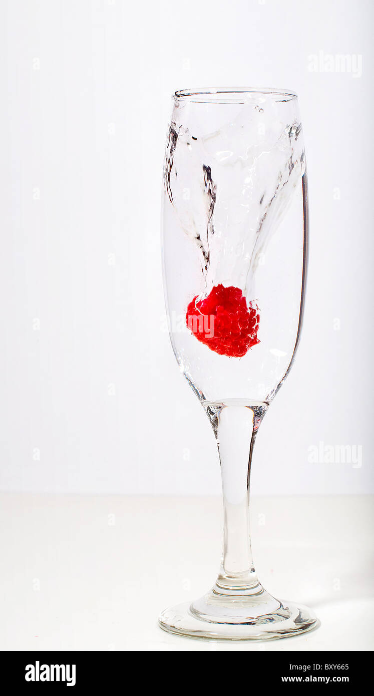 Les projections dans le verre à champagne framboise Banque D'Images