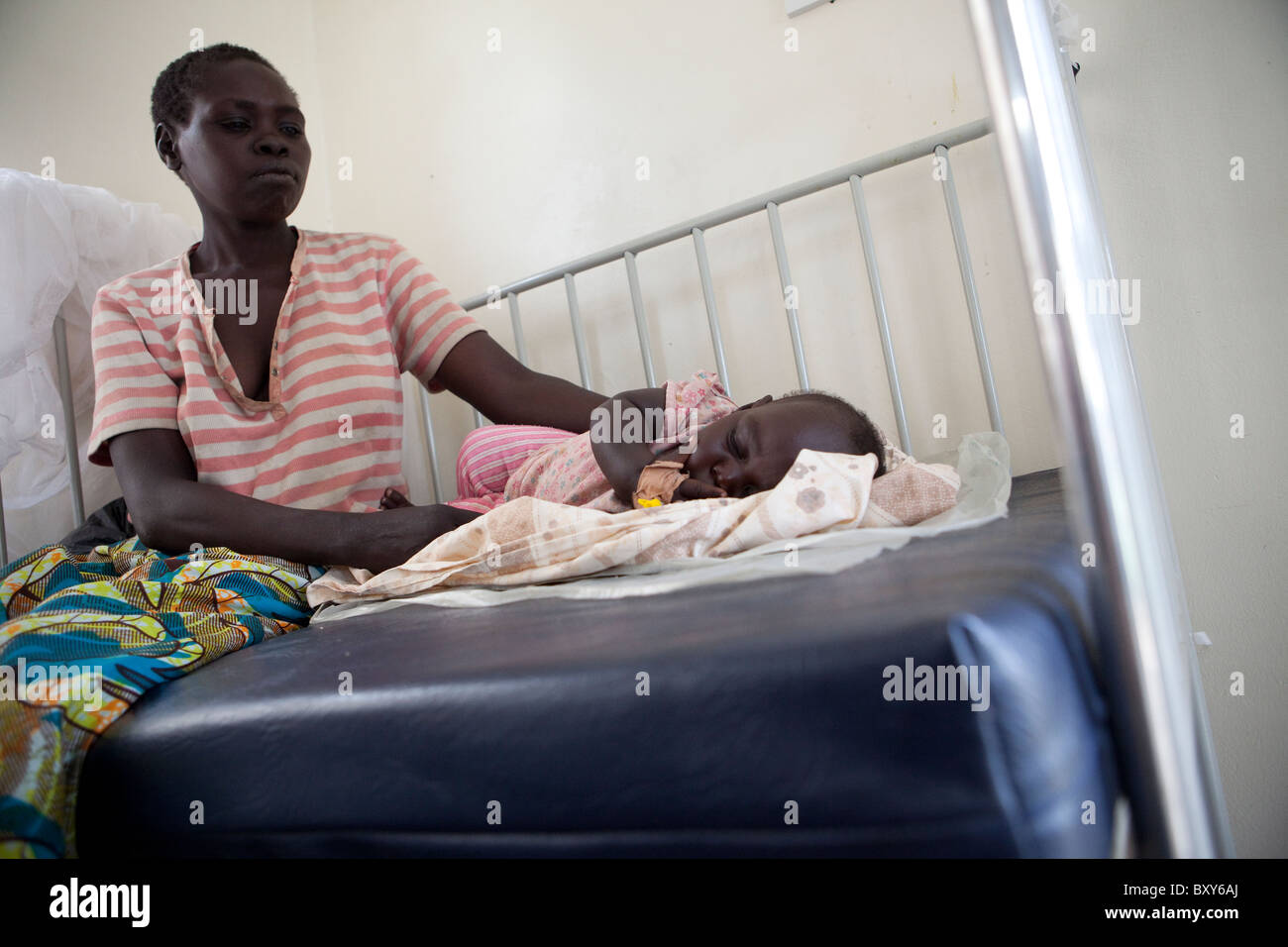 Une mère s'occupe de son jeune enfant souffrant du paludisme dans un hôpital de Amuria, dans le nord de l'Ouganda, l'Afrique de l'Est. Banque D'Images