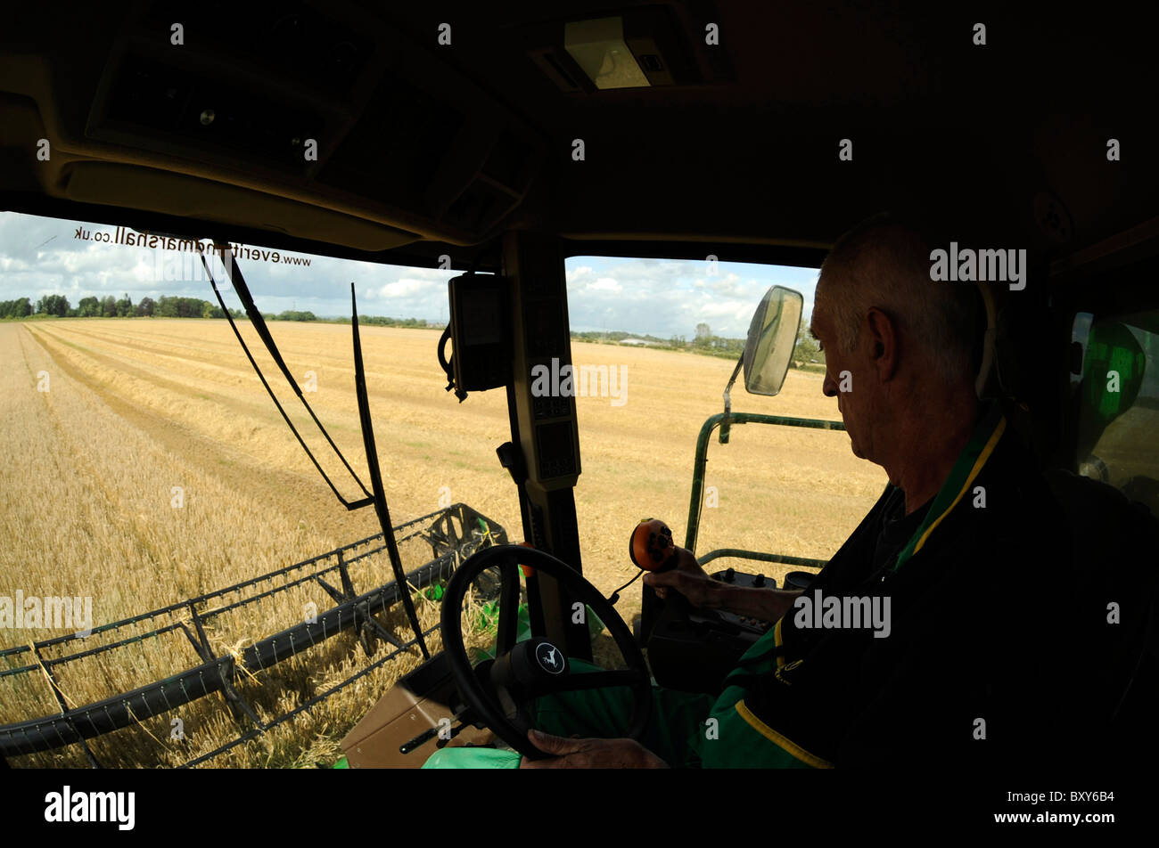 Une moissonneuse-batteuse John Deere Harvester la récolte d'orge dans un champ à Holme Gate Farm près de Warwick sur Eden Banque D'Images