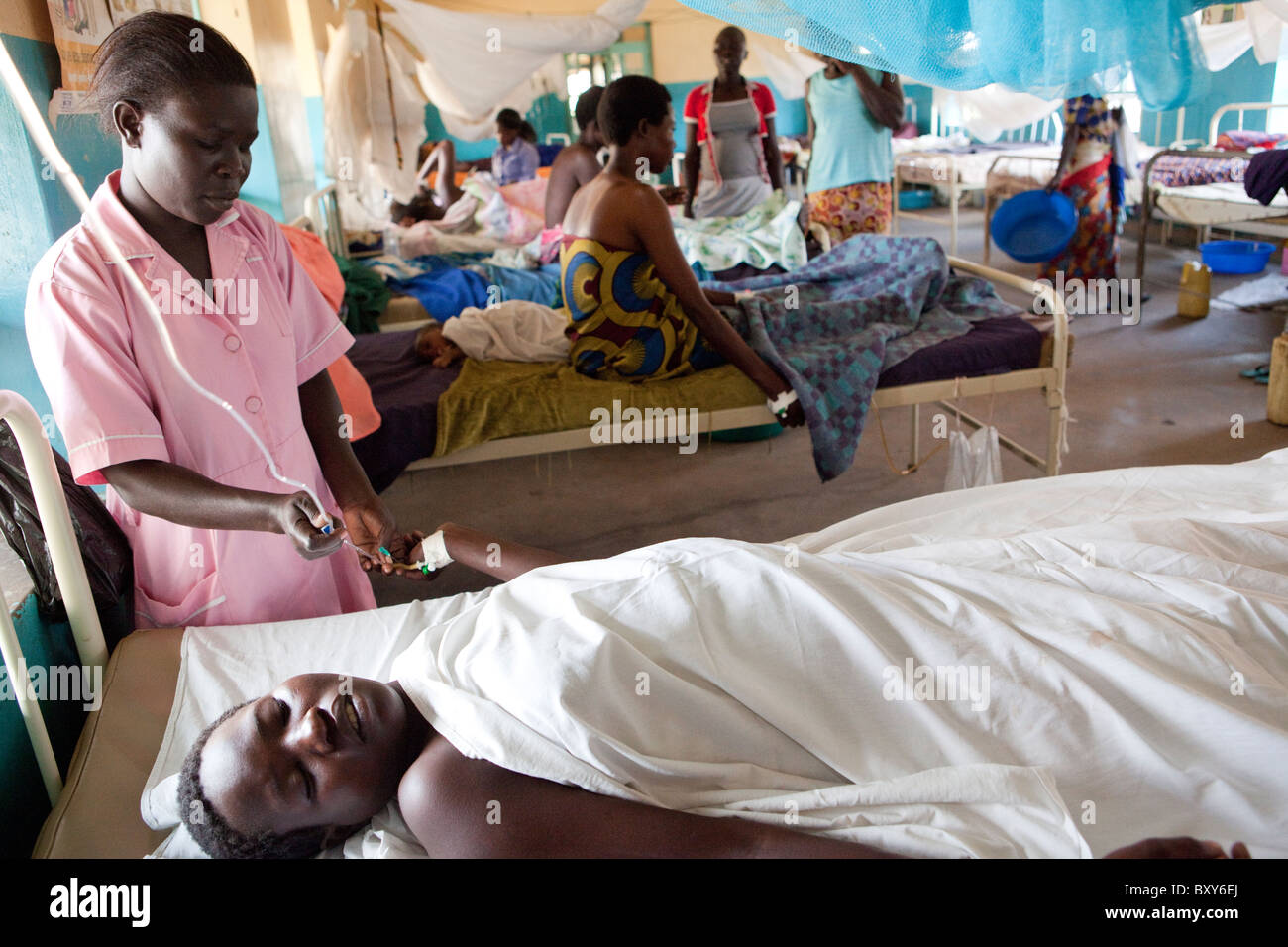 Une infirmière s'occupe d'une femme allongée, inconsciente après l'accouchement - Amuria, Ouganda, Afrique de l'Est. Banque D'Images