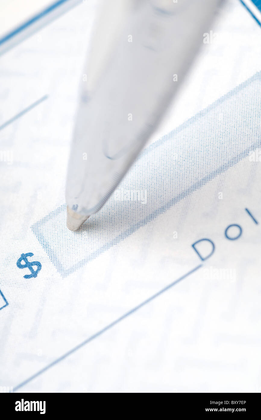 Un gros plan d'un stylo remplissant un montant du chèque Banque D'Images