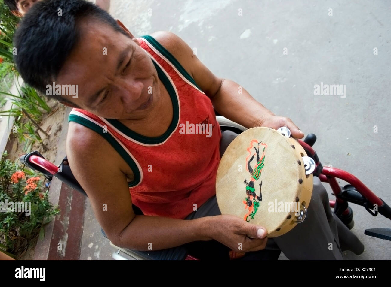 Un homme patient hôpital amputé est apprécie la musique comme thérapie par la lecture d'un tambourin d'un établissement de soins de santé au Laos communiste. Banque D'Images