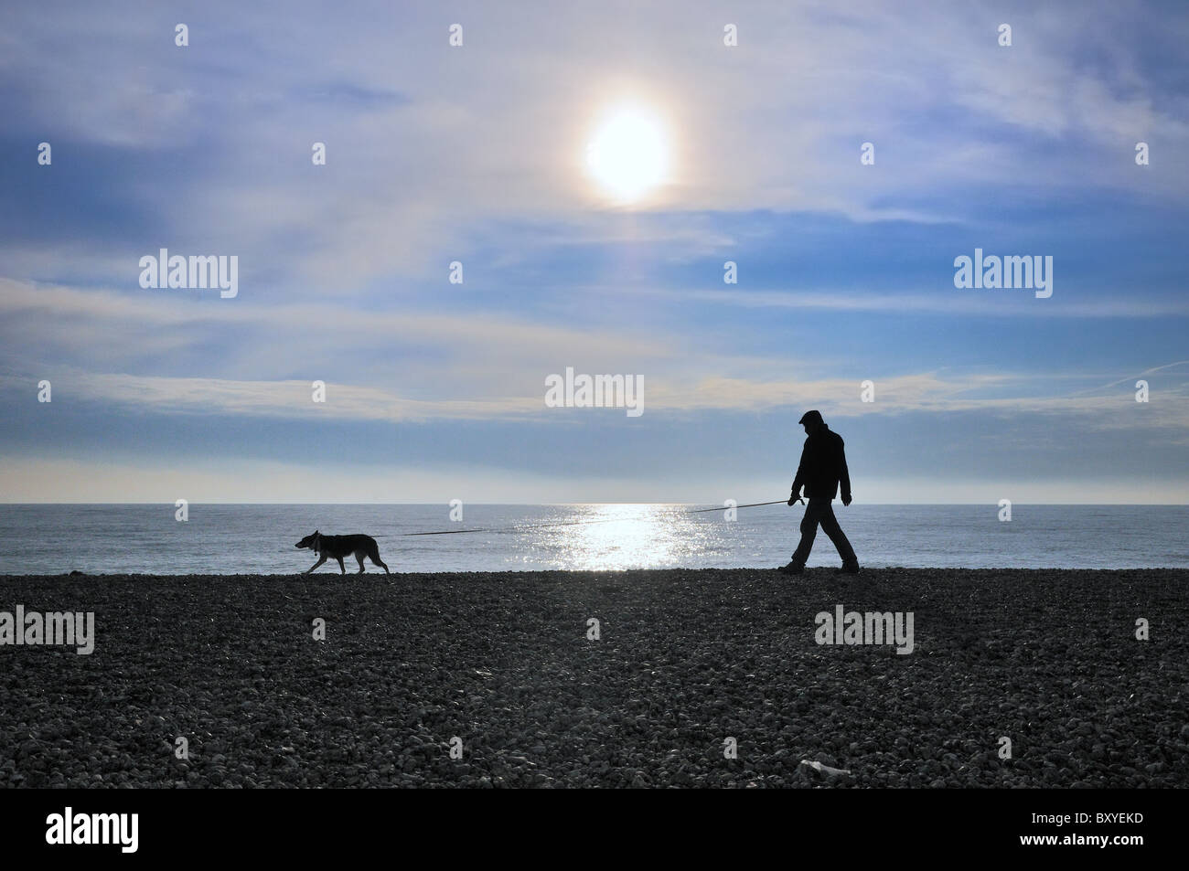 Man Walking dog sur Worthing Beach soleil en hiver Banque D'Images