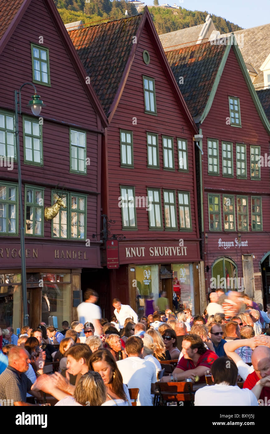 Les gens assis à trottoir bars/cafés, Bryggen, le quartier médiéval de Bergen, Hordaland, Norvège Banque D'Images