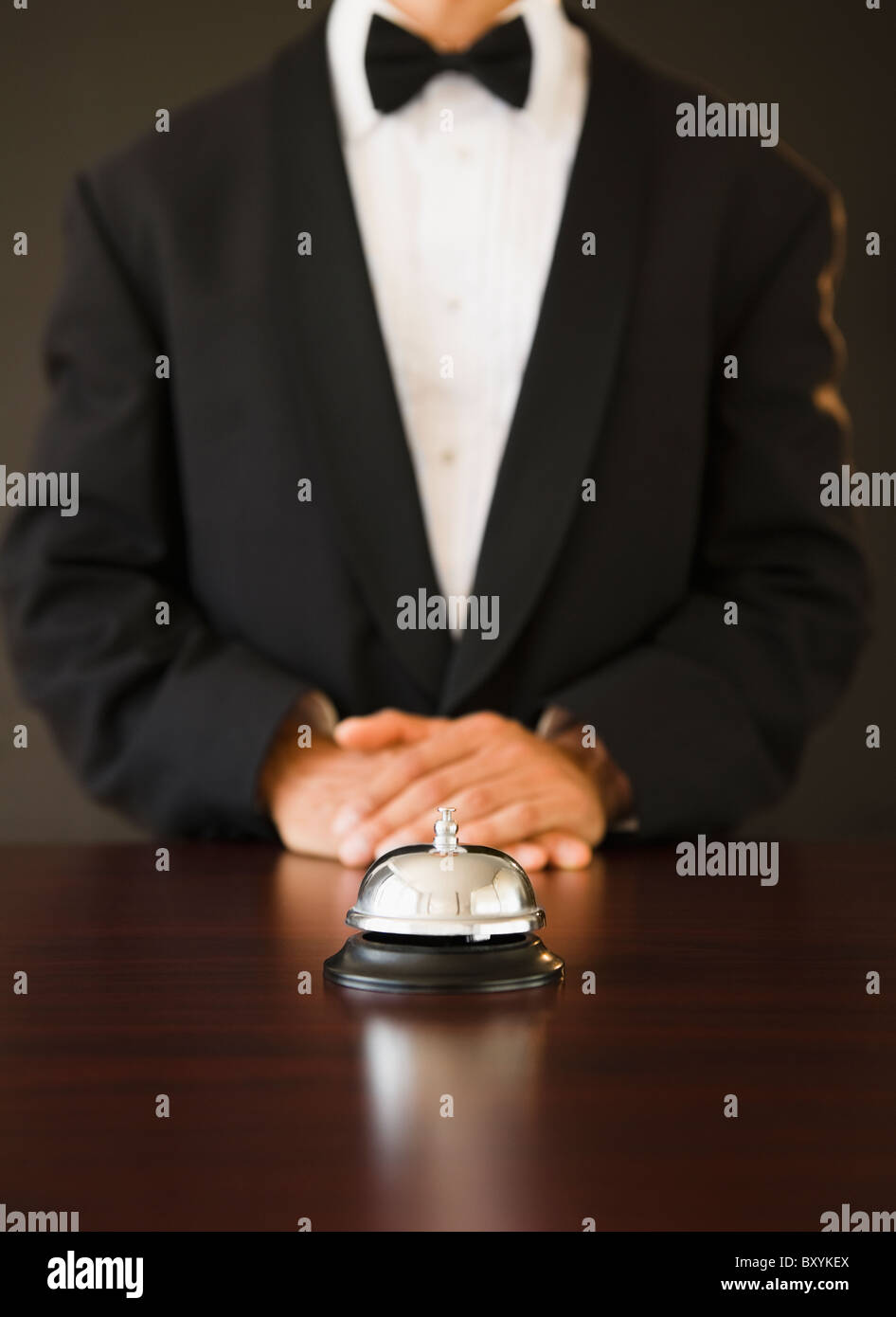 Service bell au premier plan, un homme portant cravate d'arc dans le background, studio shot Banque D'Images