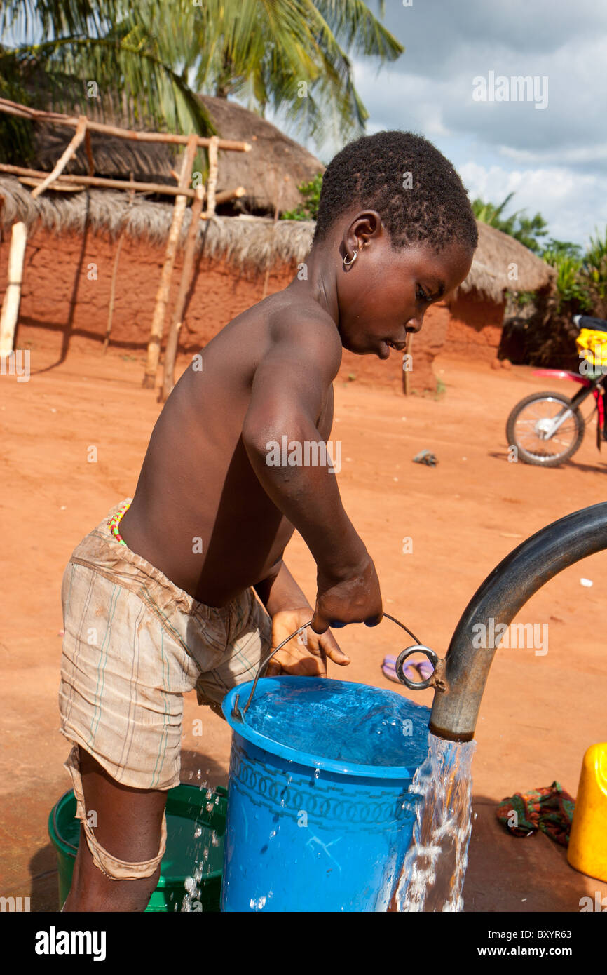 Nettoyer l'eau saine est pompée d'un bien par les enfants du village en Afrique de l'Ouest. La pompe a été installée par une ONG. Banque D'Images
