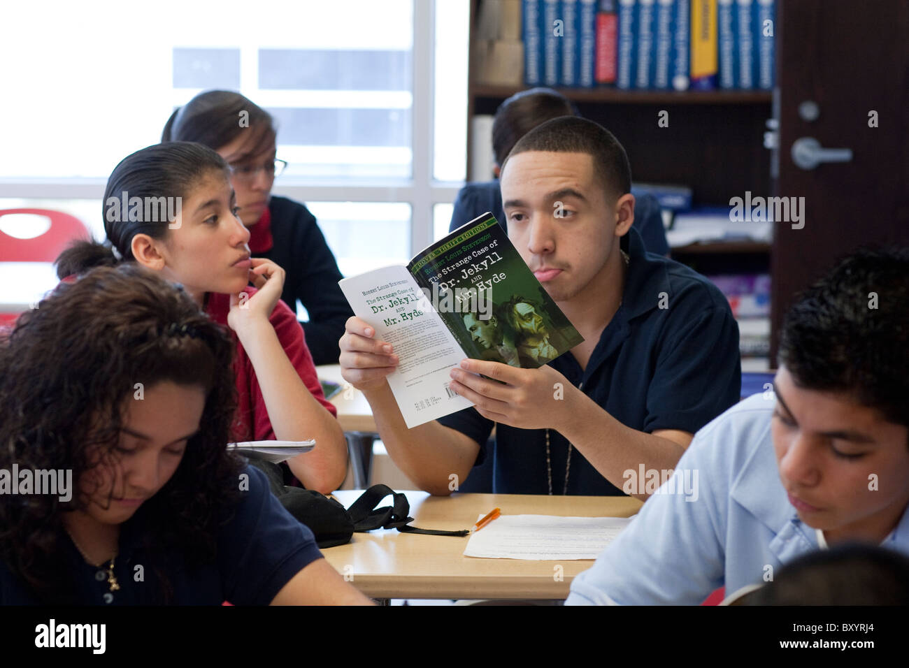 Hispanic male high school élève lit un roman en classe préparatoire au public charter school Academy à Dallas au Texas Banque D'Images