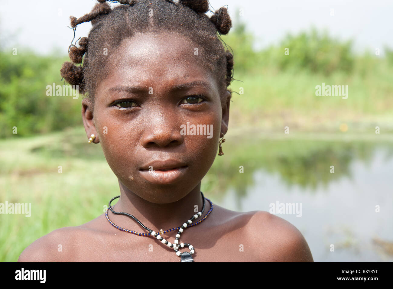 Une jeune fille dont le village a participé à un projet générateur de revenu pour améliorer la pauvreté rurale se tient près d'un étang pour la pêche. Banque D'Images