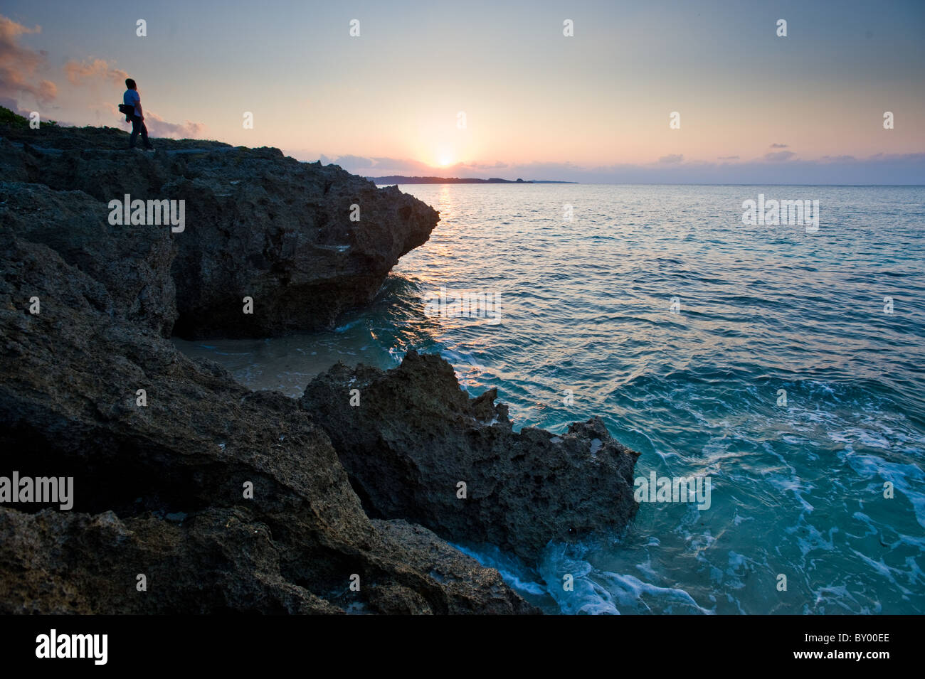 Seul visiteur regarde le coucher du soleil sur l'océan à Onna-fils (district), Okinawa Banque D'Images