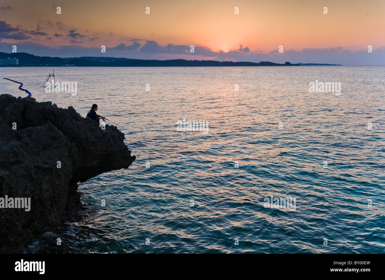 Pêcheur solitaire au coucher du soleil à Onna-fils (district), Okinawa Banque D'Images