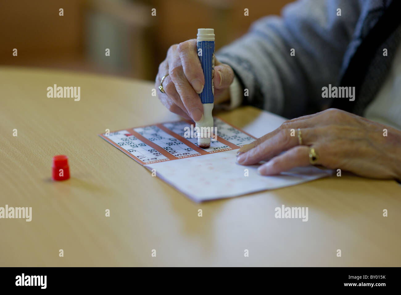 Close up image de femme âgée, marquage la main de carte de bingo sur table. Banque D'Images