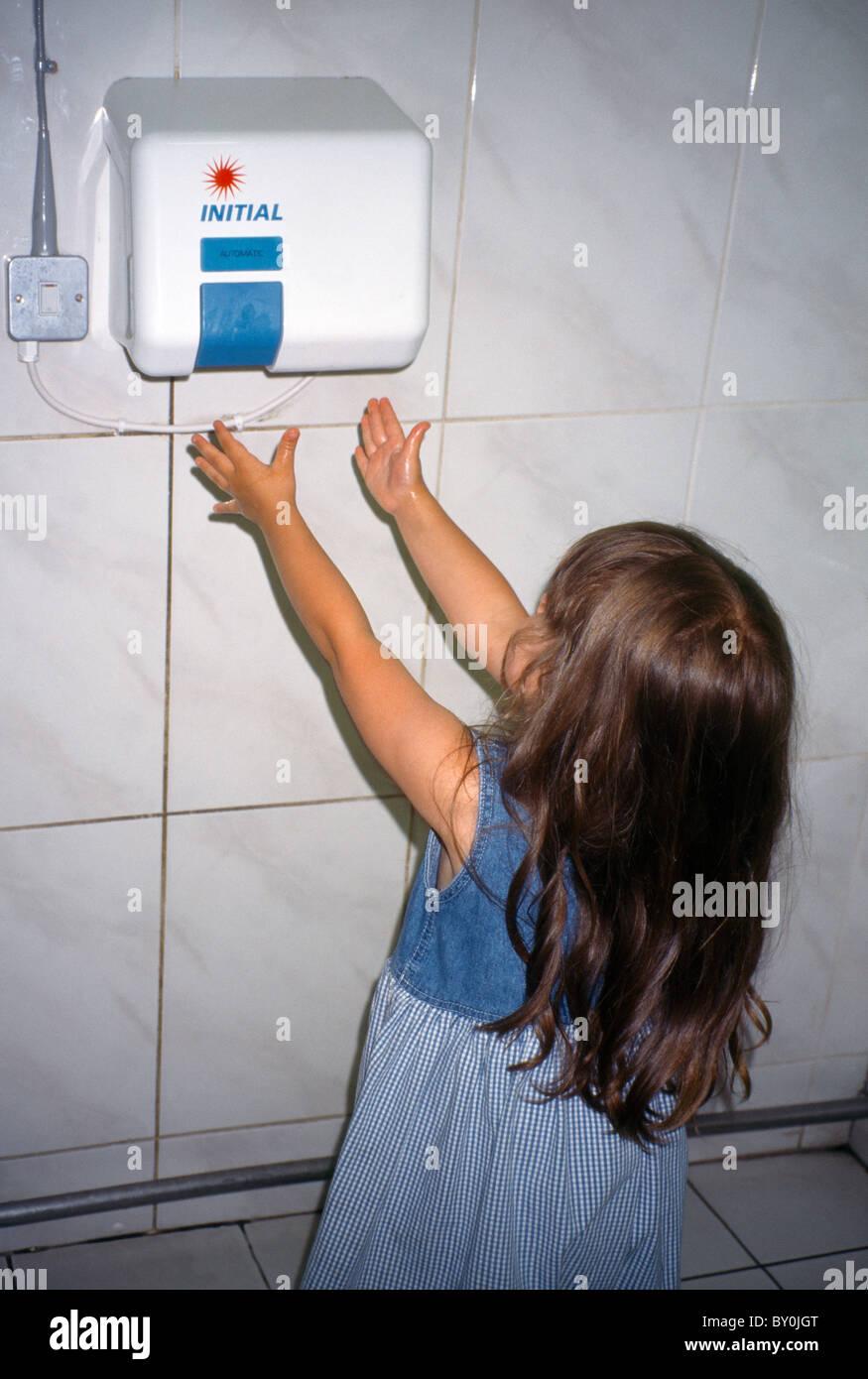 Ses mains sur le séchage de l'enfant sèche-mains électrique Banque D'Images