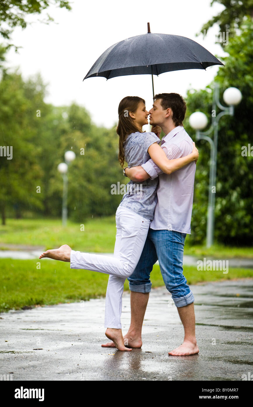Photo de couple romantique pieds nus sur la route sous la pluie et aller à baiser les uns les autres Banque D'Images