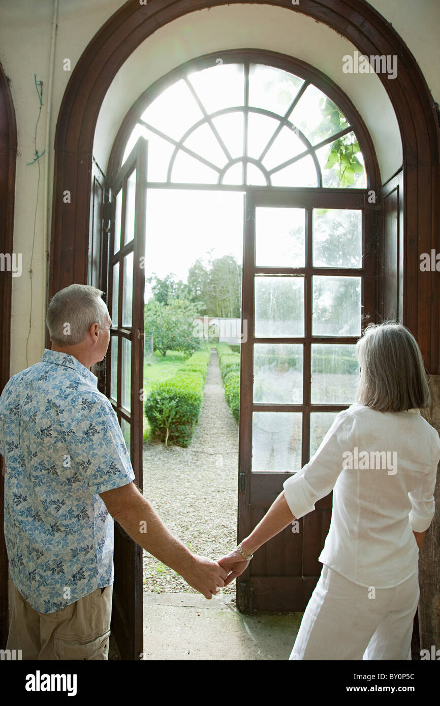 Young couple holding hands par des portes françaises Banque D'Images
