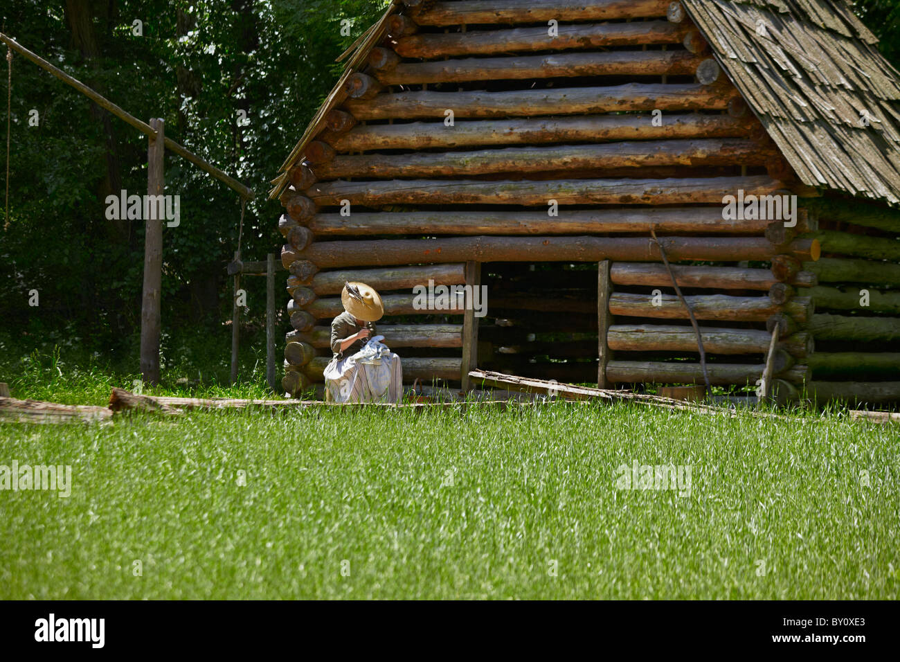 Une femme coud reenactor dans la lumière du soleil à Claude Moore Colonial Farm, McLean, Virginia. Banque D'Images