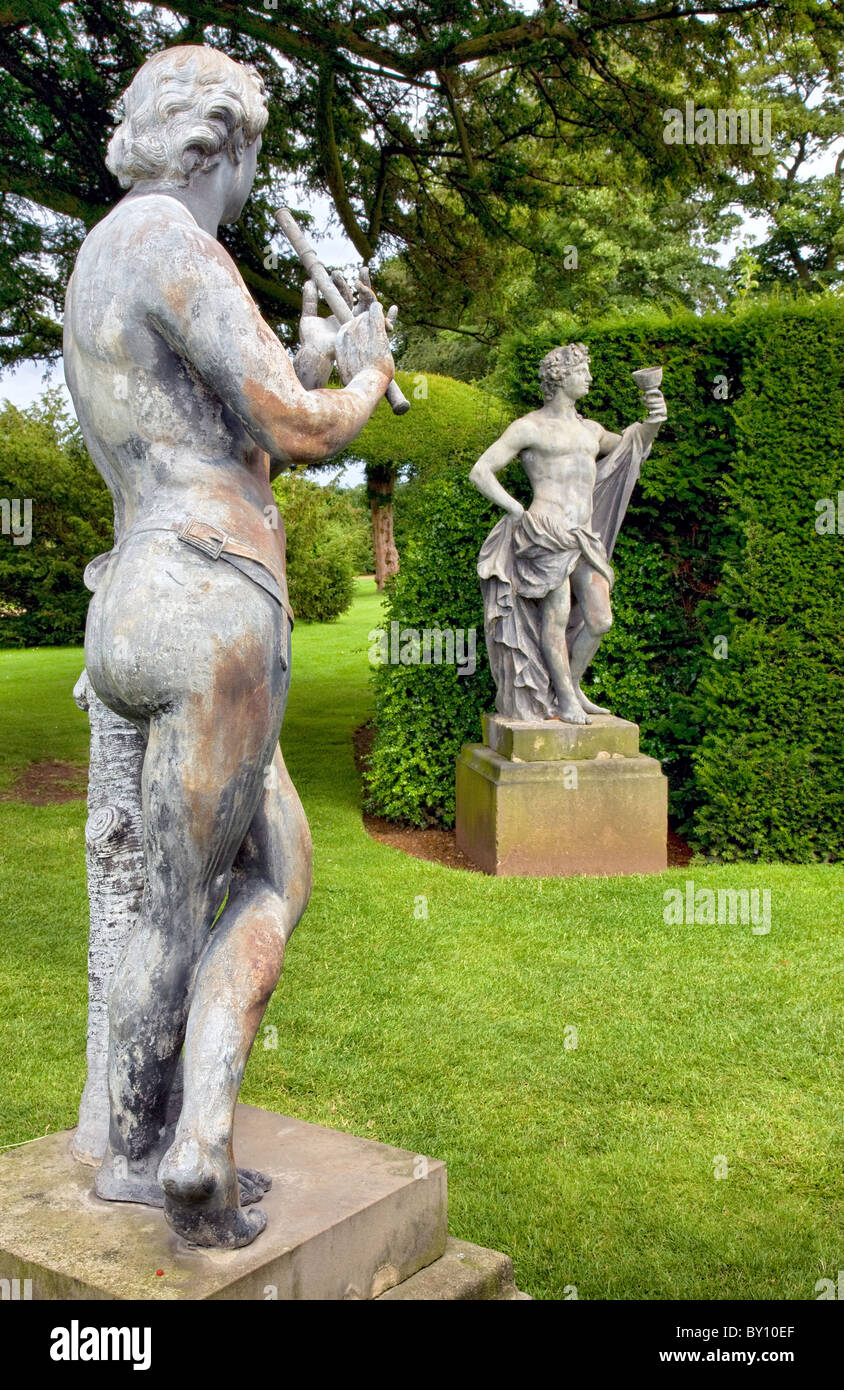 Le jardin de sculptures de plomb à peine vêtues d'un joueur de flûte et d'un gobelet potable Bacchus flanquent le yew à pied à Hardwick Hall Banque D'Images