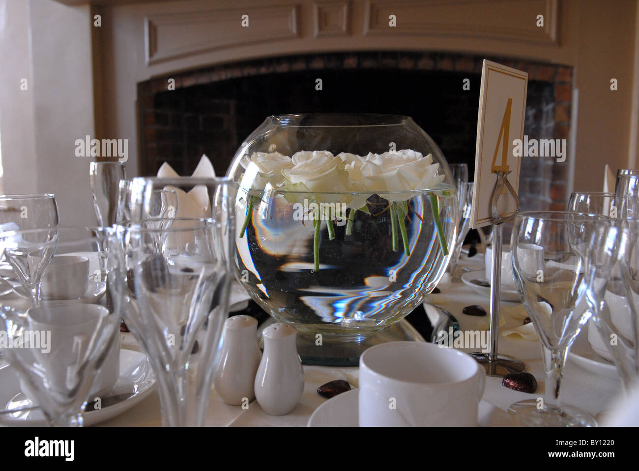 Roses ivoire flottant dans un bol d'eau sur une table de dîner à une réception de mariage Banque D'Images