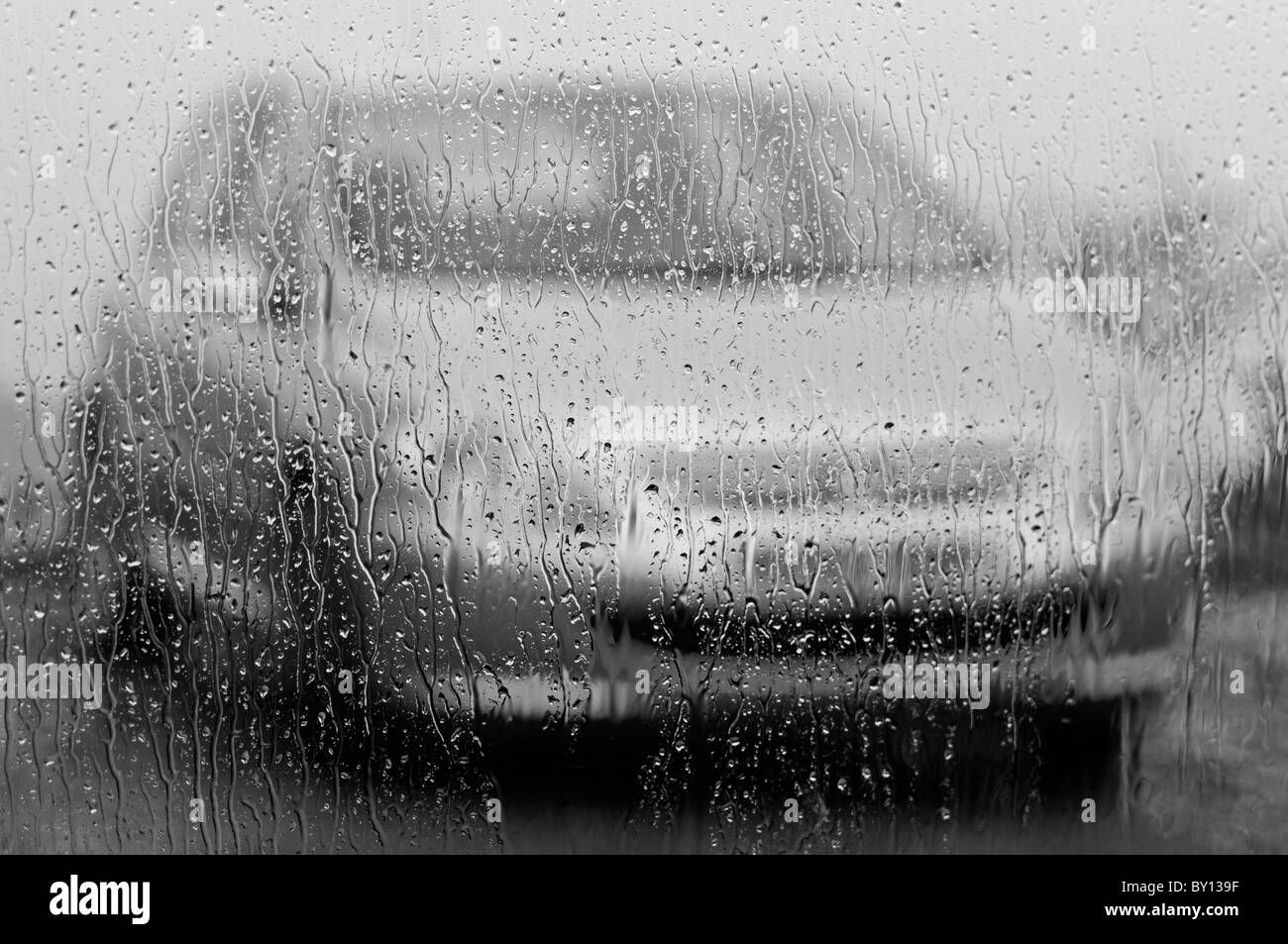 La pluie fouettant contre une fenêtre de cuisine, noir et blanc. Banque D'Images