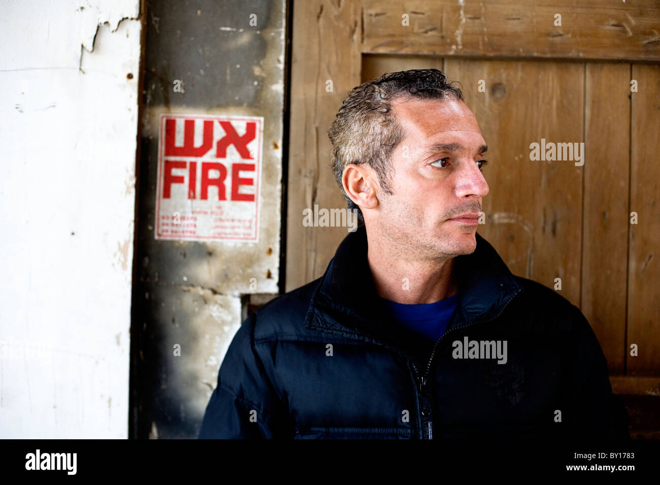 L'homme dans son 40s en situation urbaine portant des tenues à la mode et debout devant une vieille porte Banque D'Images