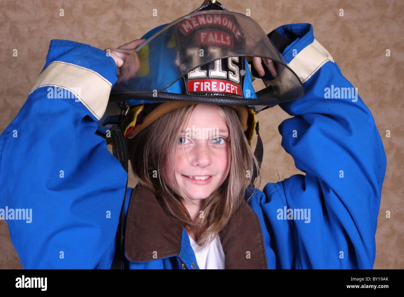 Une jeune fille habillé en firewoman dans son casque de pompier Banque D'Images