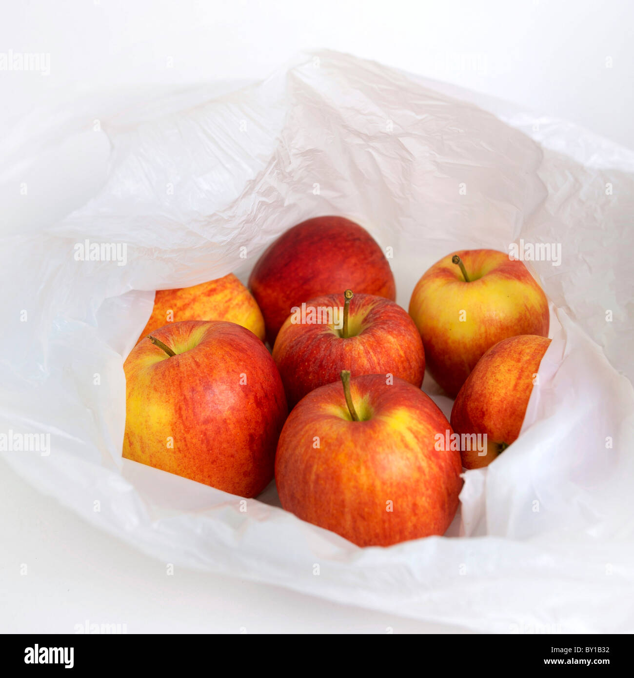 Pommes fraîches dans un sac en plastique blanc présenté avec un éclairage doux dans un environnement minimaliste Banque D'Images