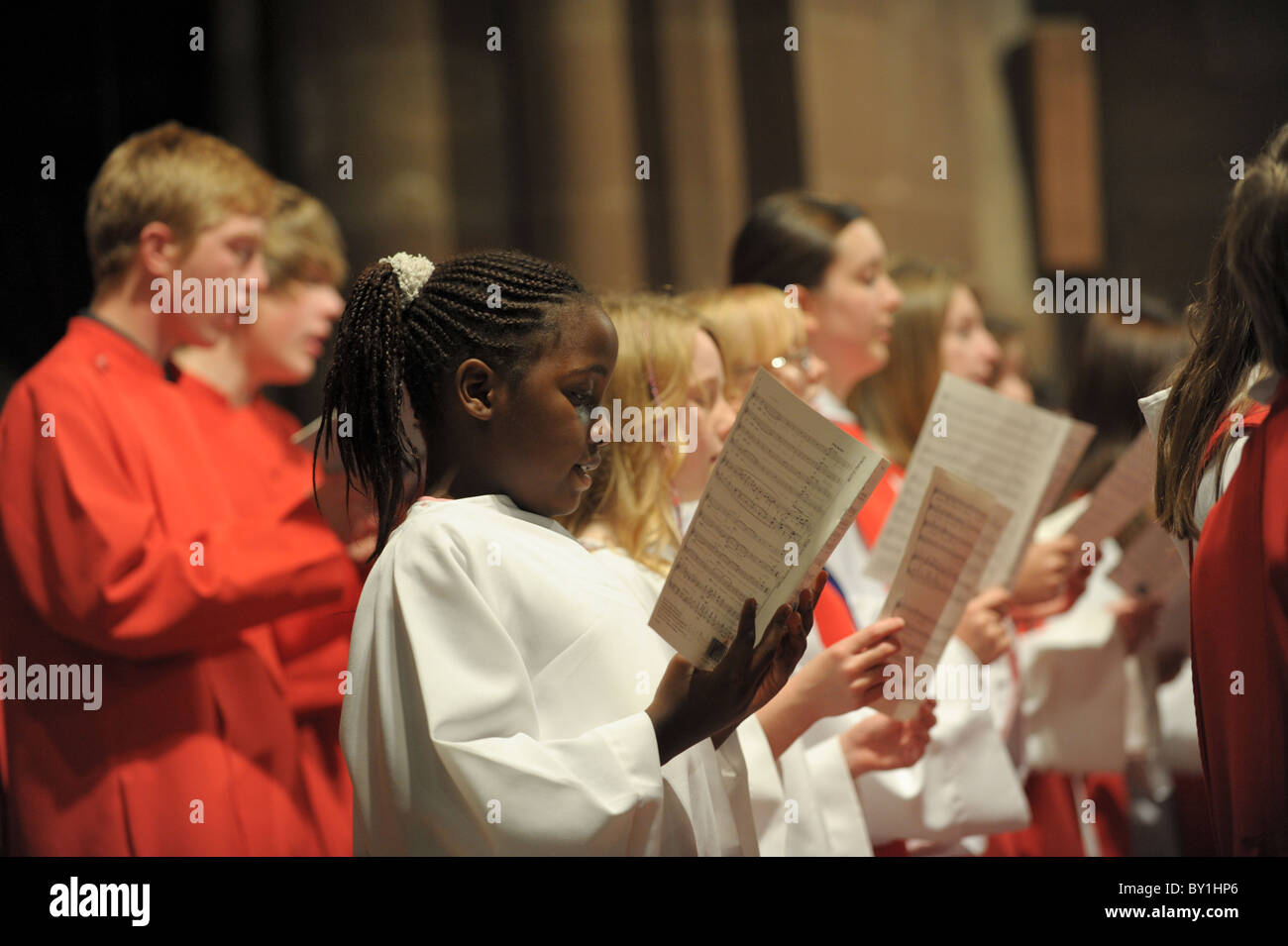 Chorale à l'Église avec les enfants noirs et blancs en soutanes holding sheet music pratiquer pour un concert de chant choral Banque D'Images