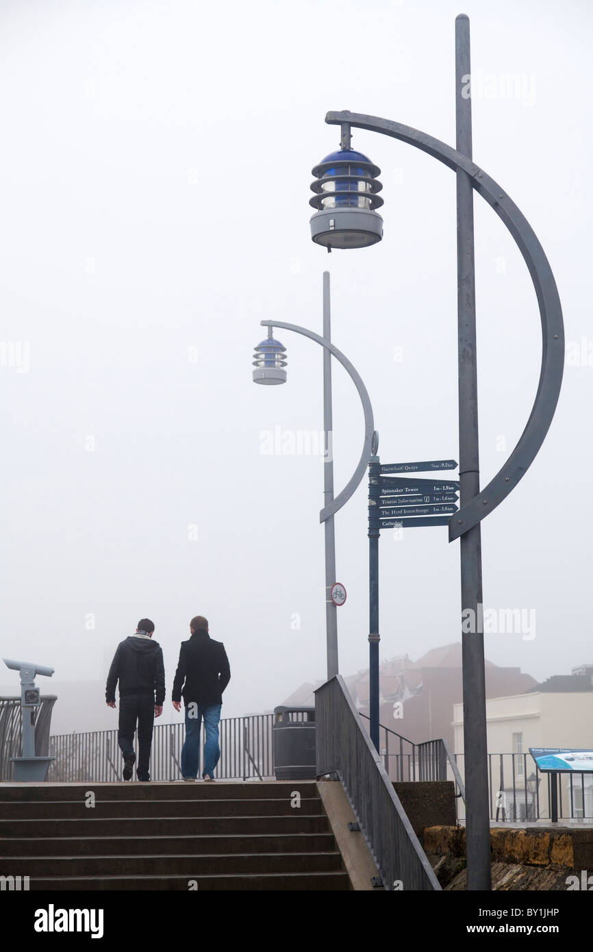 Marcher sur le mur de la mer dans le brouillard avec les lampes de rue Banque D'Images