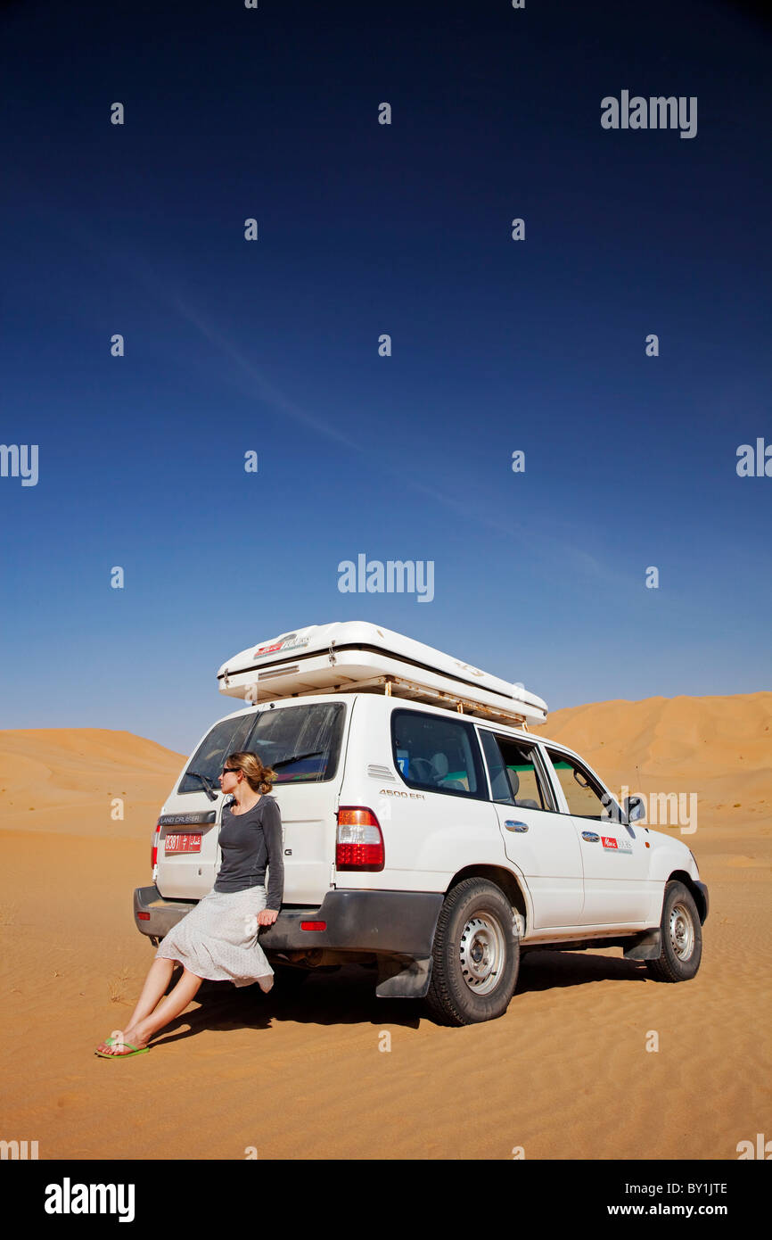Oman, quart vide. Une jeune femme prend une pause de conduire pour profiter de la vue. Banque D'Images