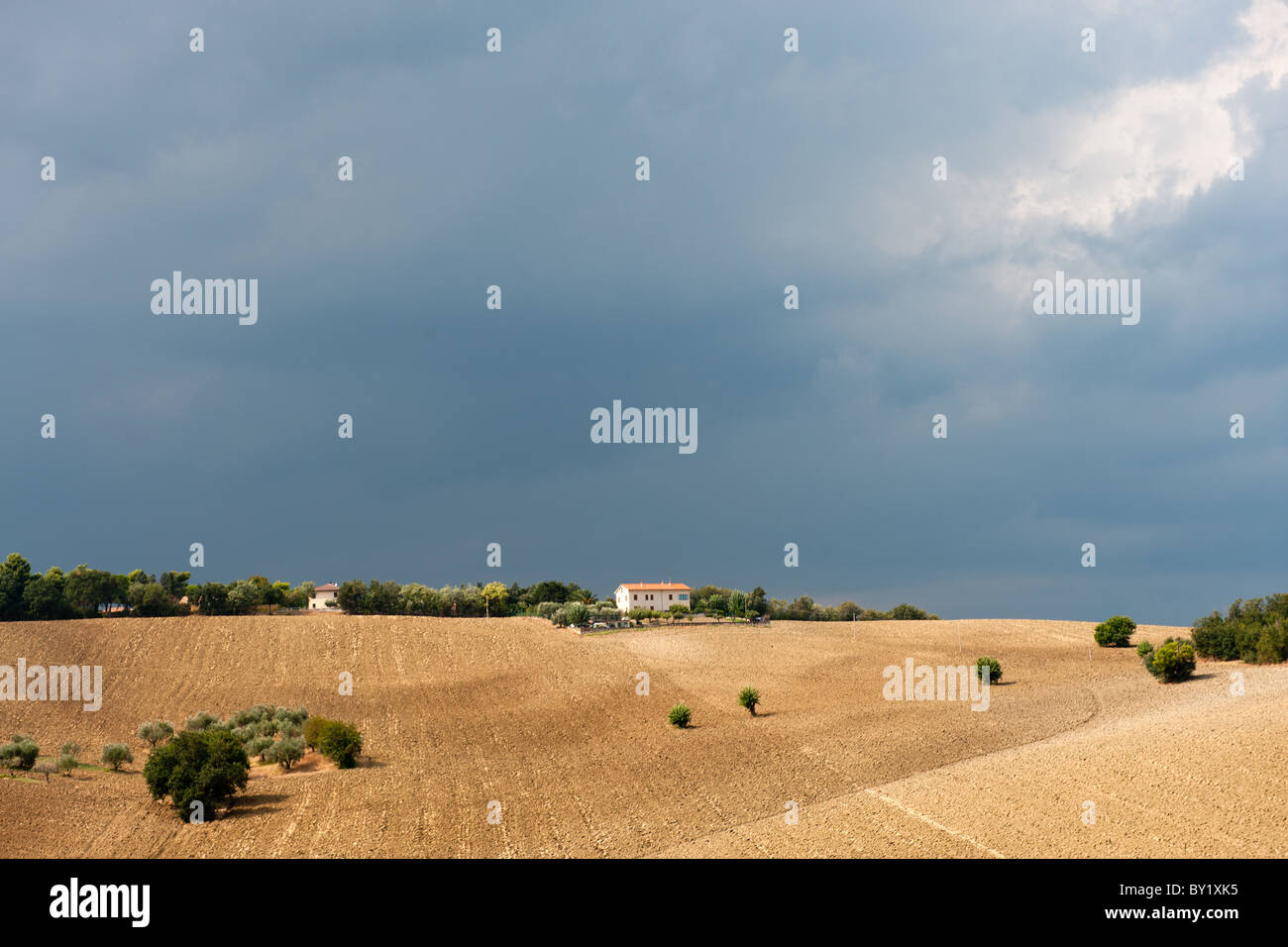 Ciel noir derrière un paysage italien avec une maison sur la colline Banque D'Images