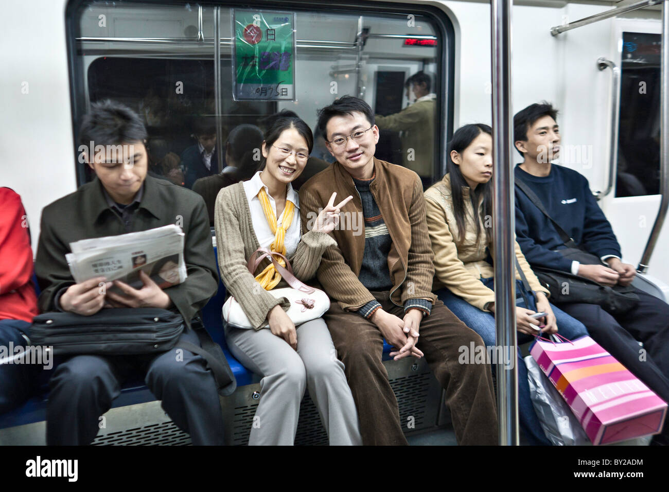 La CHINE, Beijing : Happy young couple chinois le métro de Pékin et donner le signe de la paix à d'autres voyageurs. Banque D'Images