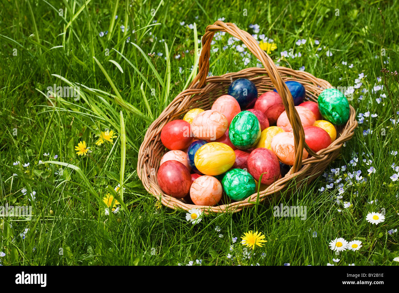 Panier plein d'œufs de Pâques dans l'herbe Banque D'Images