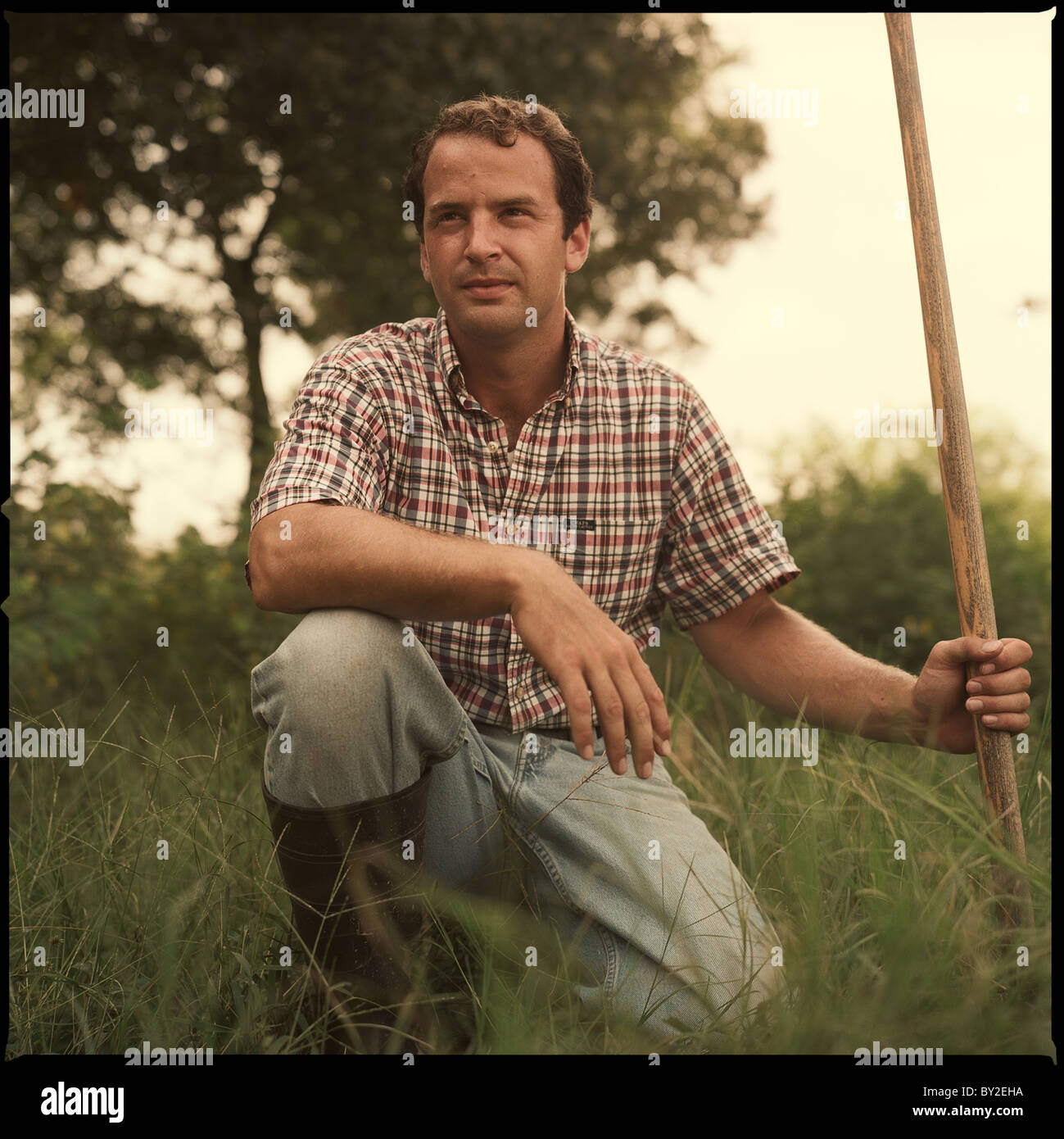 Un homme pose pour un portrait dans certaines hautes herbes sur sa ferme de l'ampoule dans l'Est du Texas Banque D'Images