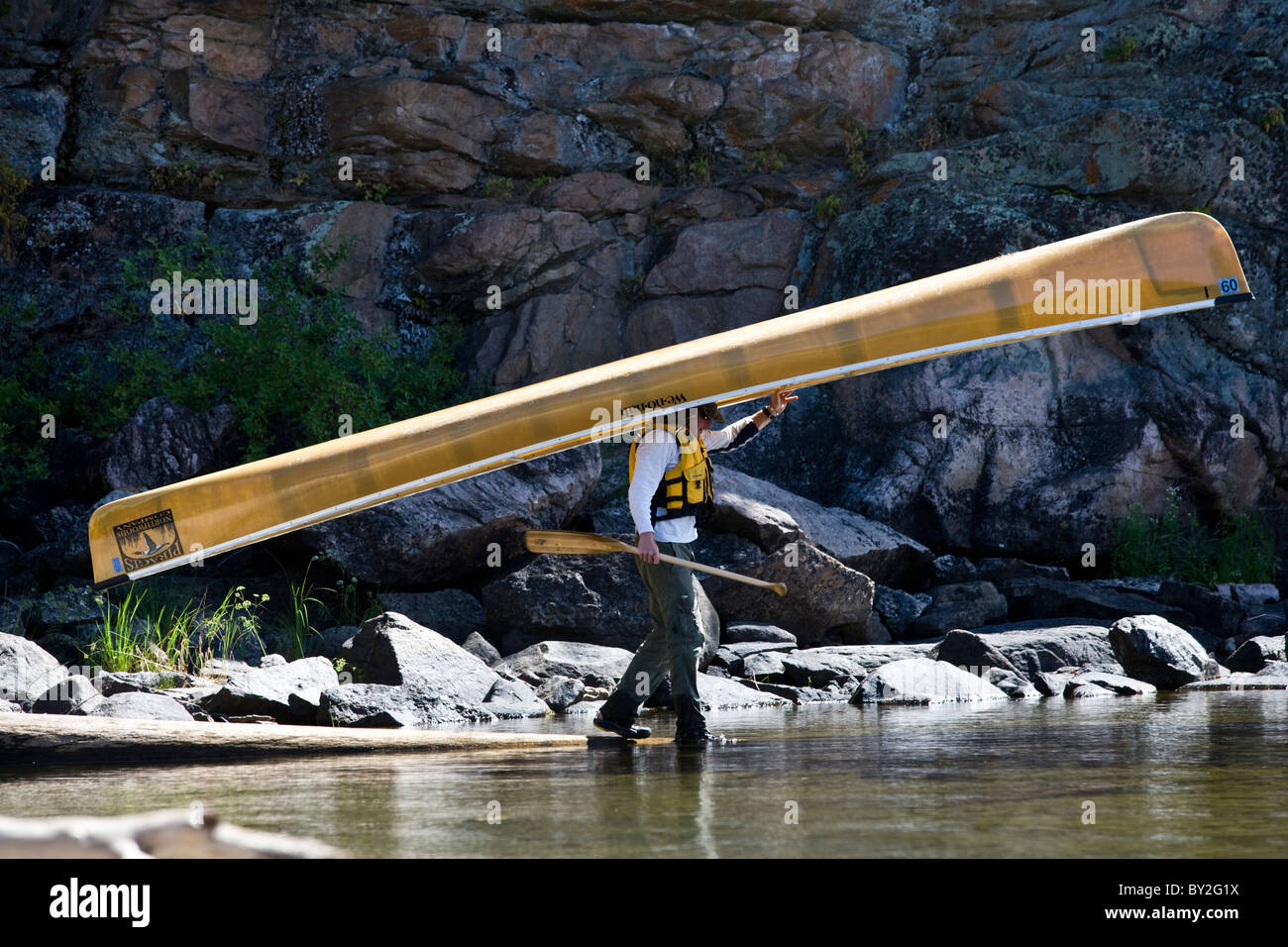 Un jeune passionné de l'eau transporte son canot sur la tête en entrant dans les eaux limitrophes du Minnesota. Banque D'Images