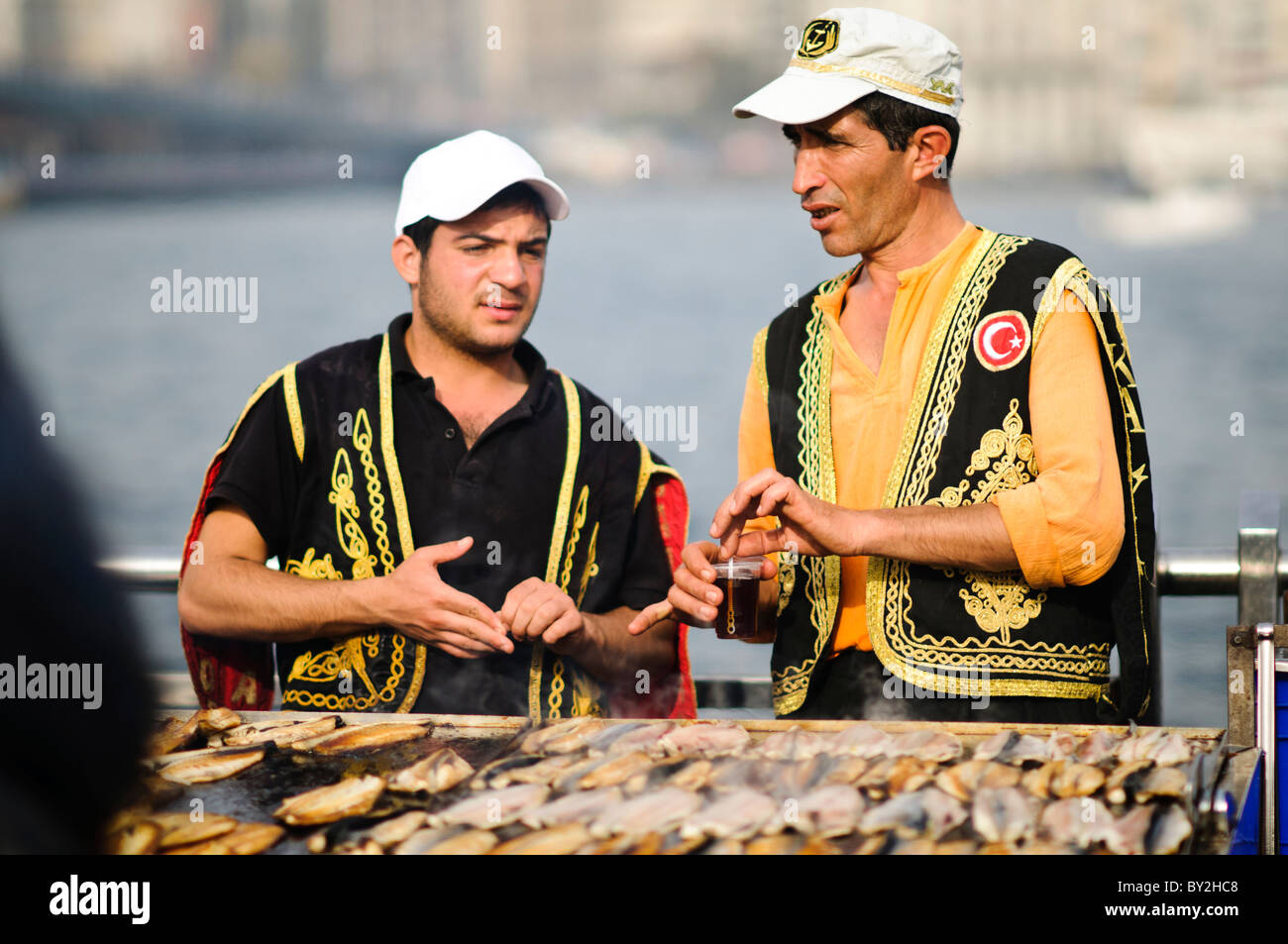 Balik Ekmek Fish Sandwich Street Food Eminonu Istanbul // ISTANBUL, Turquie — Un vendeur de rue fait griller du poisson frais sur le front de mer d'Eminonu, près du pont de Galata, préparant le traditionnel balik ekmek (sandwich au poisson). Le balik ekmek, généralement préparé avec du maquereau grillé servi dans du pain blanc avec des oignons et de la laitue, est l'un des plats de rue les plus populaires d'Istanbul. Les vendeurs de poissons riverains opèrent à partir de bateaux flottants et de stands le long de la Corne d'Or à cet endroit depuis des générations. Le quartier d'Eminonu sert de terminal de ferry majeur et de plaque tournante commerciale reliant l'Europe d'Istanbul et l'ASI Banque D'Images