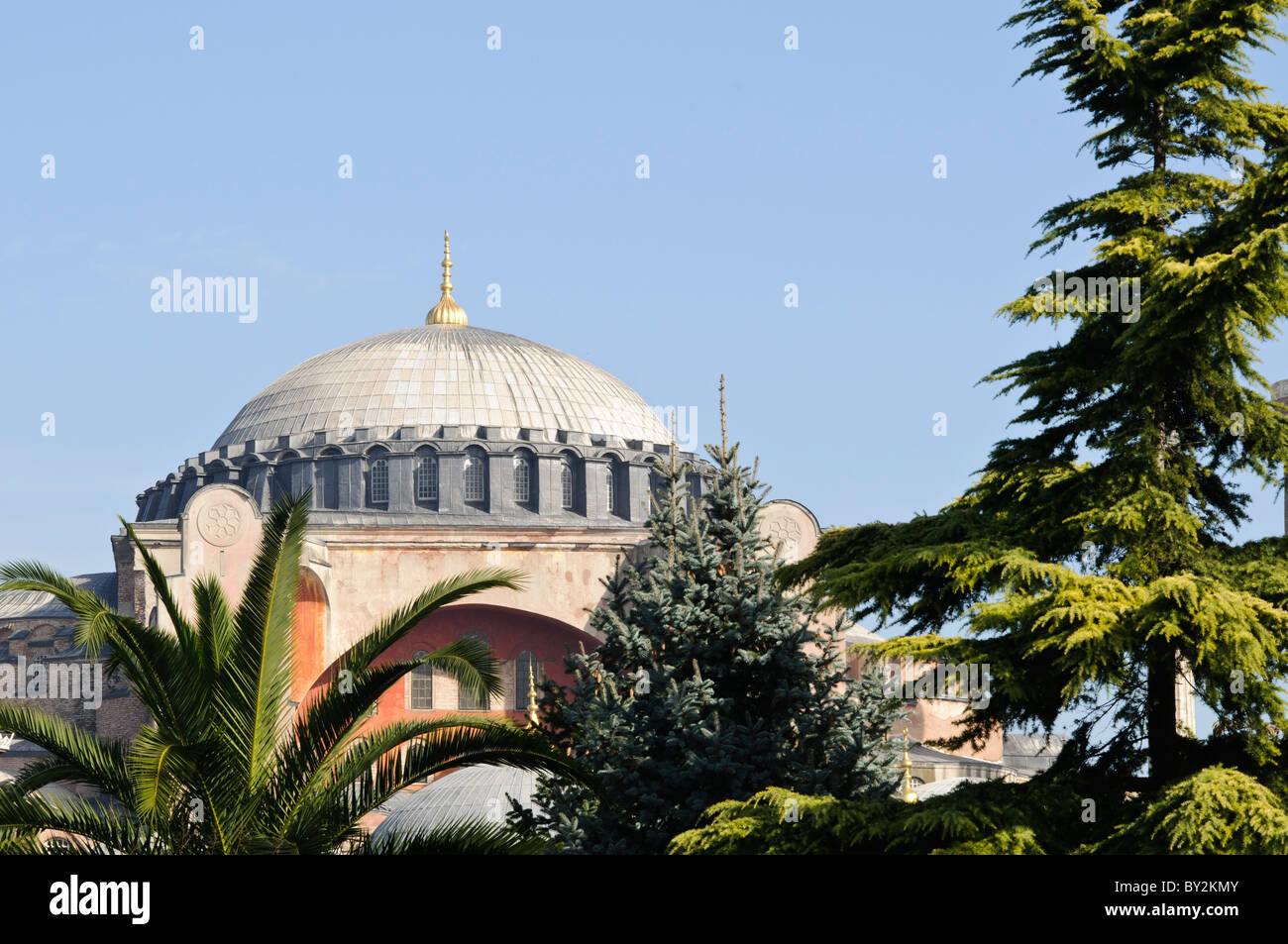 Hagia Sophia dômes et minarets Istanbul Turquie // ISTANBUL, Turquie — la basilique Sainte-Sophie vue depuis le parc du Sultan Ahmet, montrant ses dômes, minarets et contreforts distinctifs contre la ligne d'horizon d'Istanbul. L'extérieur du bâtiment reflète à la fois ses origines byzantines et ses ajouts ottomans, avec le dôme central flanqué de quatre minarets ajoutés après sa conversion en mosquée en 1453. Banque D'Images