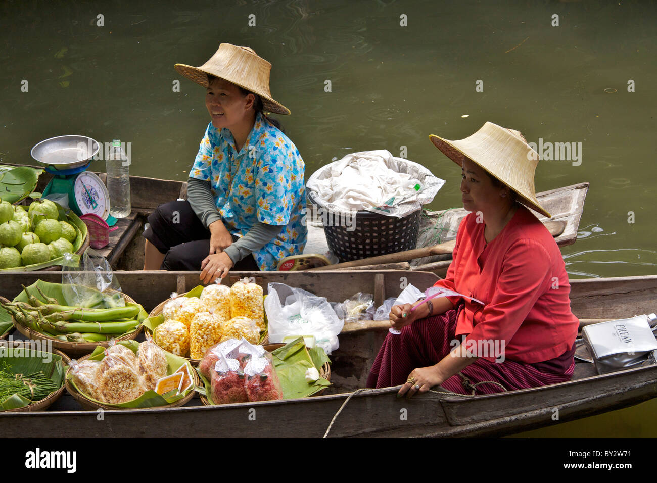 Deux dames vendent des fruits et d'autres produits alimentaires dans les bateaux en bois traditionnels sur un canal latéral dans le 'Village' culturel Thaï Banque D'Images