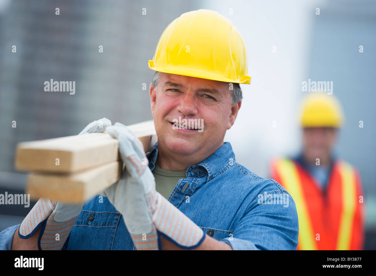 USA, New Jersey, Jersey City, Portrait of construction worker carrying planks Banque D'Images