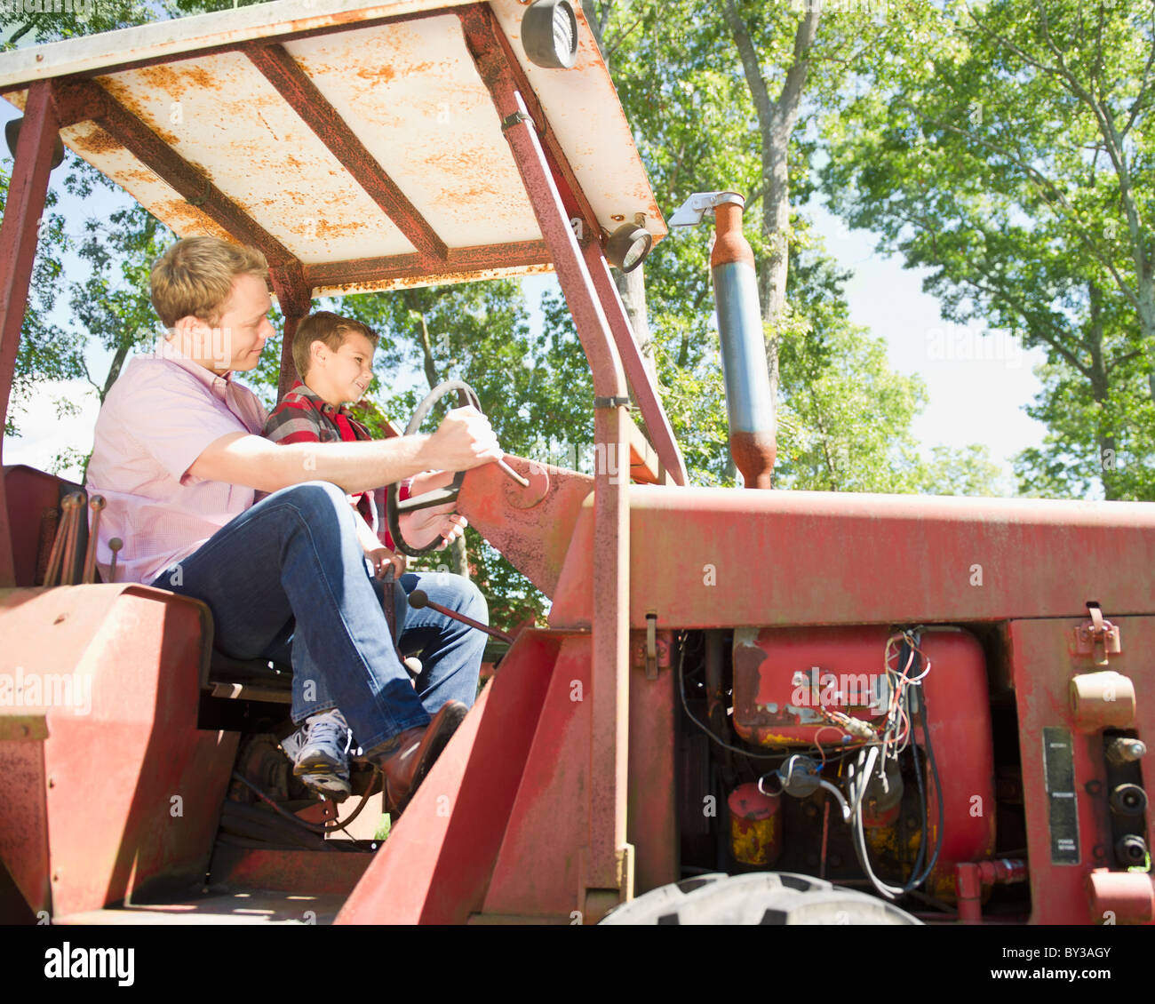 USA (New York), Flandre, Boy (8-9) avec le père assis sur le tracteur Banque D'Images