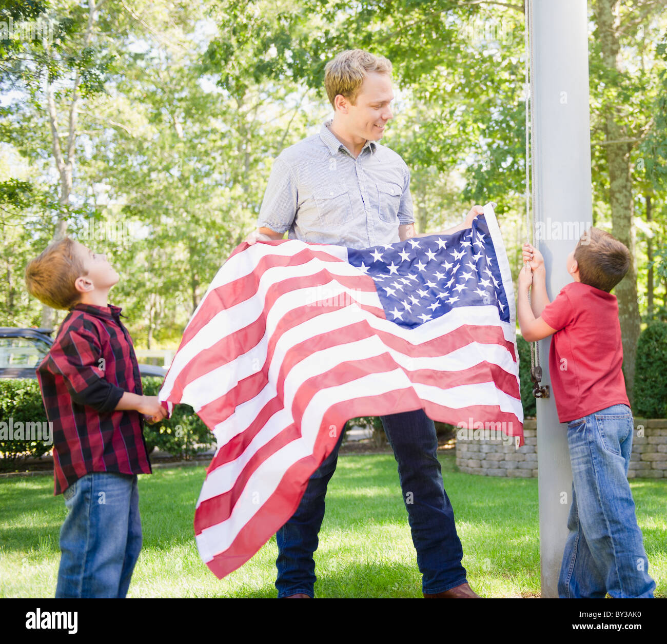 USA (New York), Flandre, père de deux garçons (4-5, 8-9) hanging drapeau américain sur perche Banque D'Images