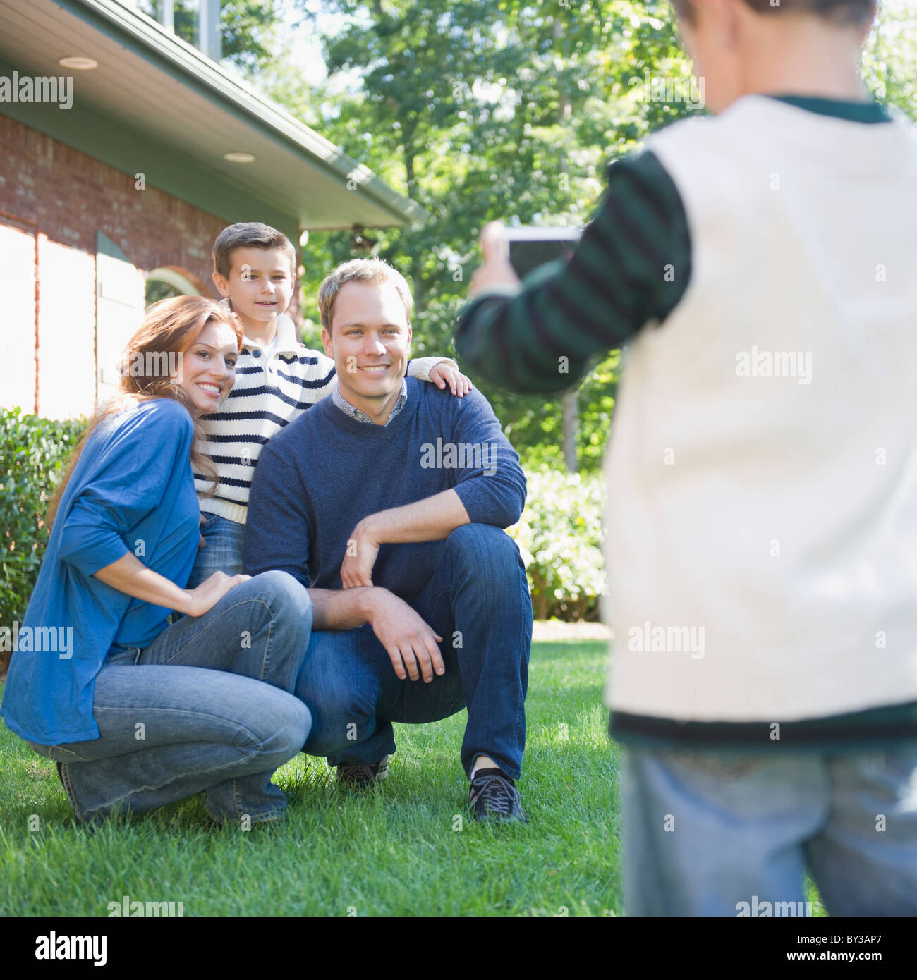 USA (New York), Flandre, Boy (4-5) taking photograph de mère, père et frère (8-9) Banque D'Images