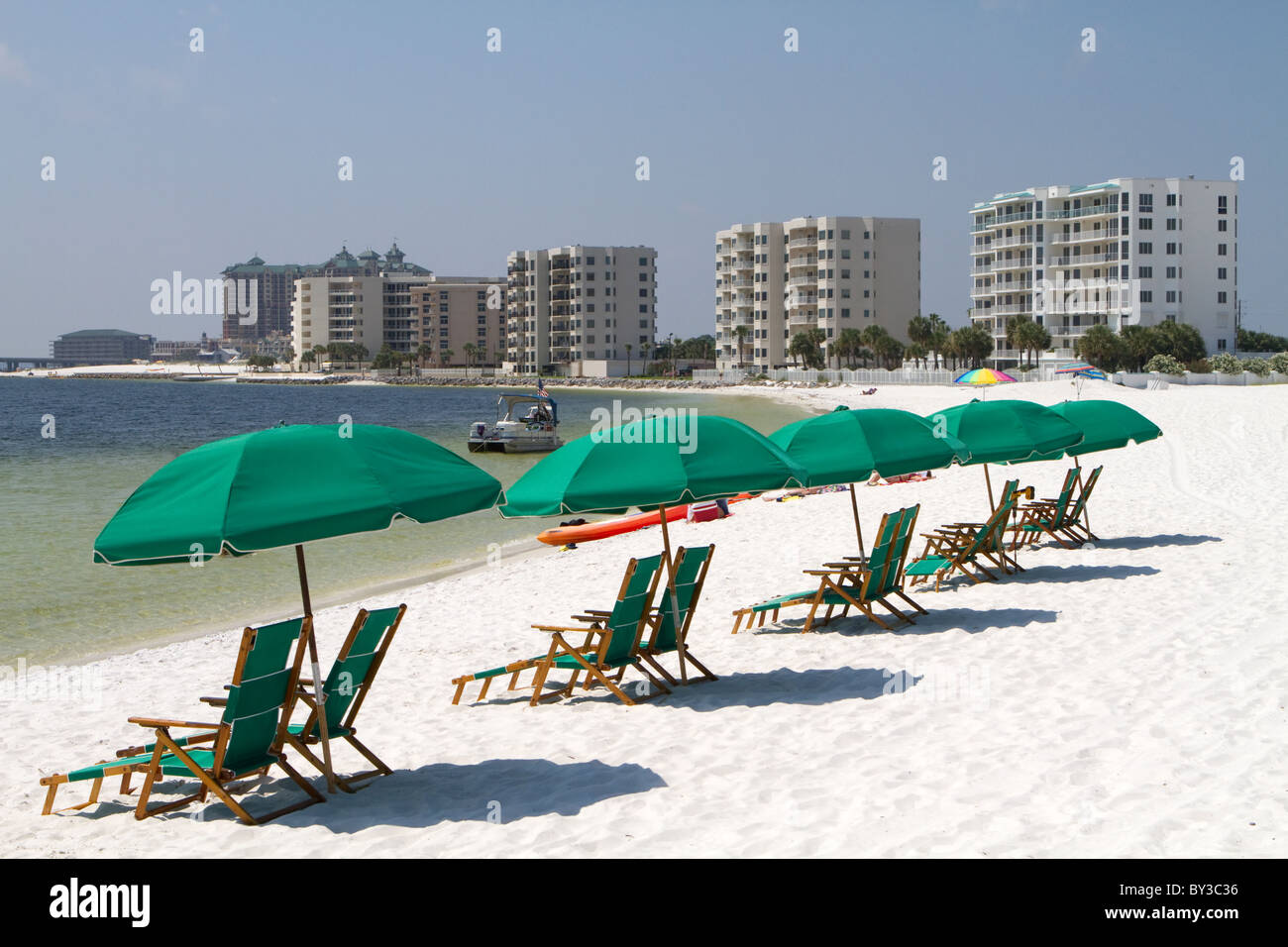 Les touristes vous détendre allongé sur la plage derrière les parasols et chaises de plage avec les tours d'immeubles en copropriété dans l'arrière-plan. Banque D'Images