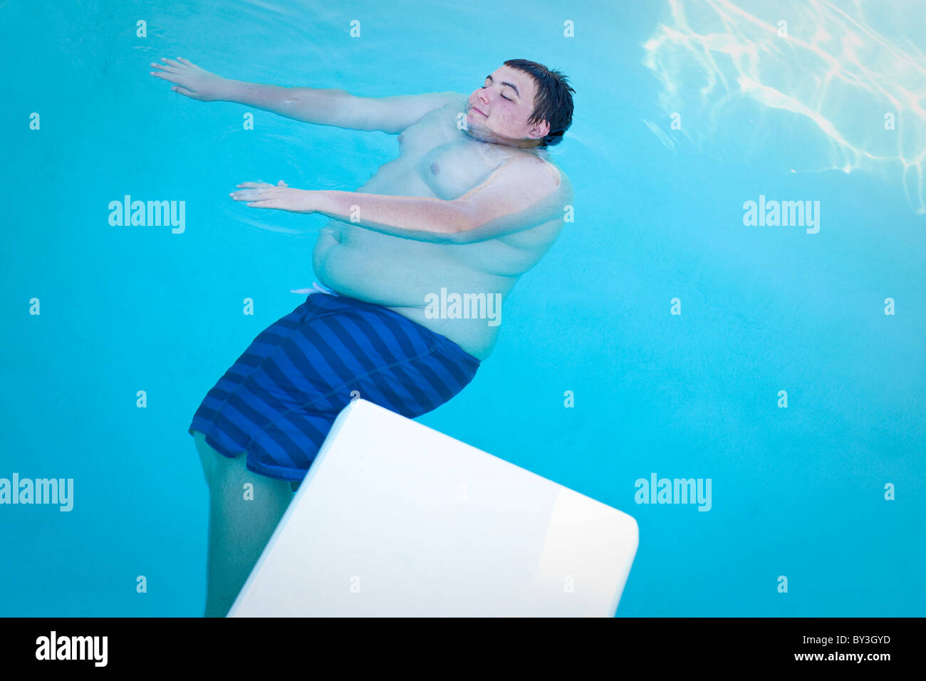 Hughson, California, United States. Un adolescent obèse flotte dans une piscine. Banque D'Images