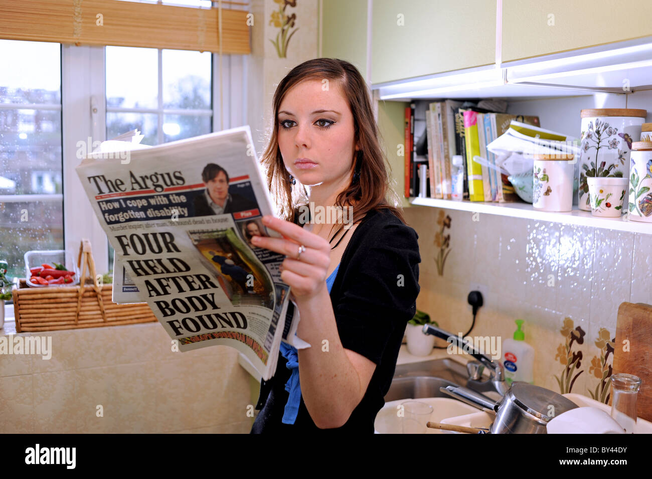 Jeune femme lisant le Brighton Sussex l'Argus daily journal régional administré par le Groupe Newsquest Banque D'Images